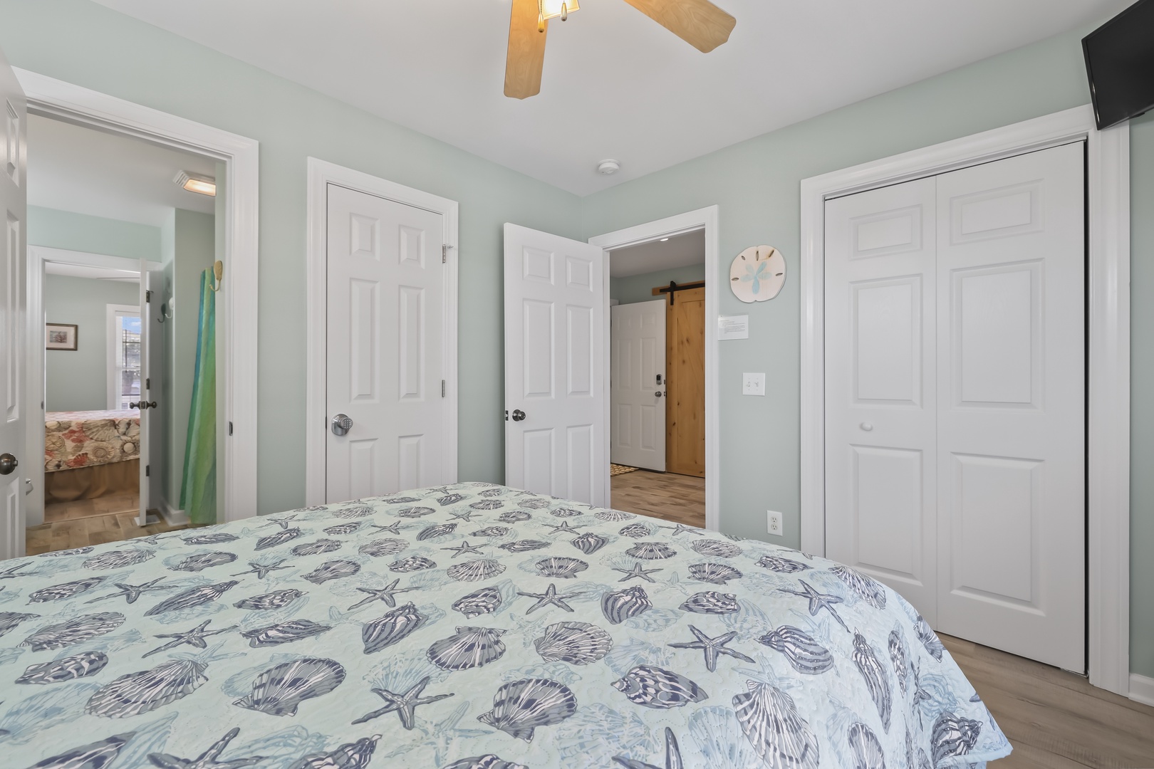 Step into your serene coastal bedroom, where soothing seafoam walls and seashell-patterned linens create a peaceful retreat. Ample storage awaits in your walk-in closet, while a ceiling fan keeps you comfortable.