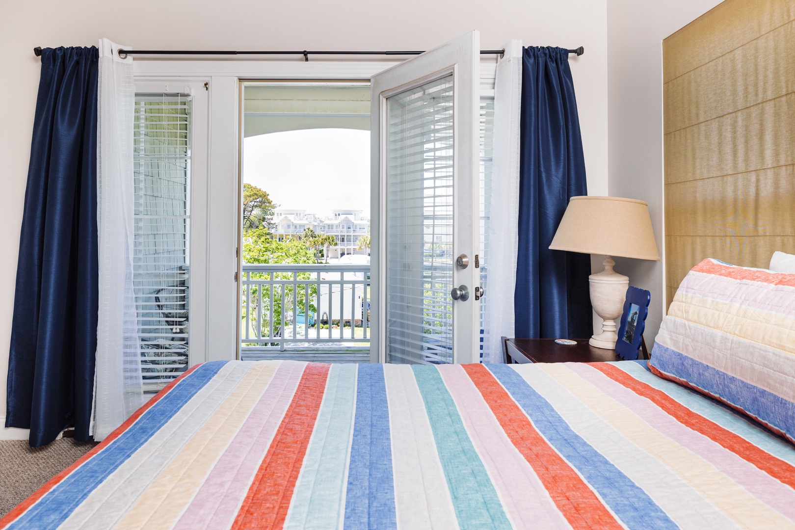 Wake up to cheerful striped bedding and open your balcony doors to let fresh air flow through your bright, coastal bedroom.