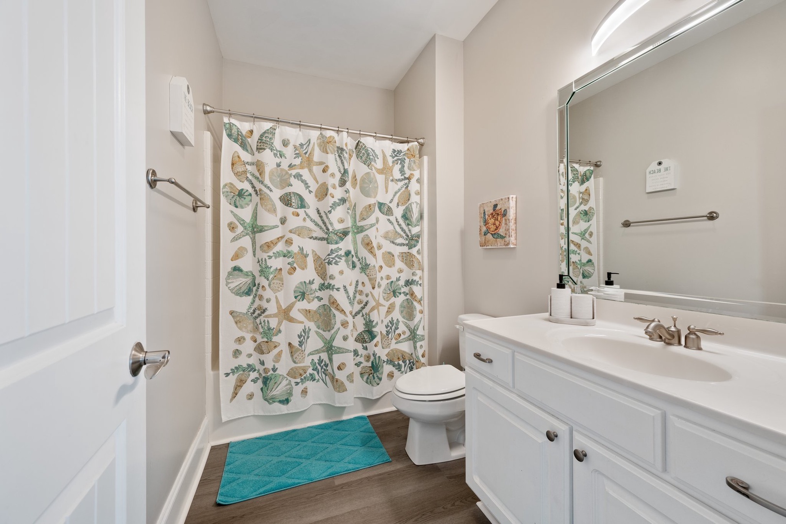 Your bathroom features a charming seashell-themed shower curtain and turquoise accents that bring coastal vibes to your morning routine.