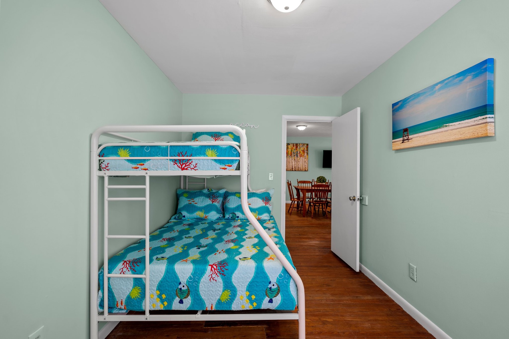Your little ones will love this fun bunk bed setup with cheerful ocean-themed bedding and a beach painting overhead.
