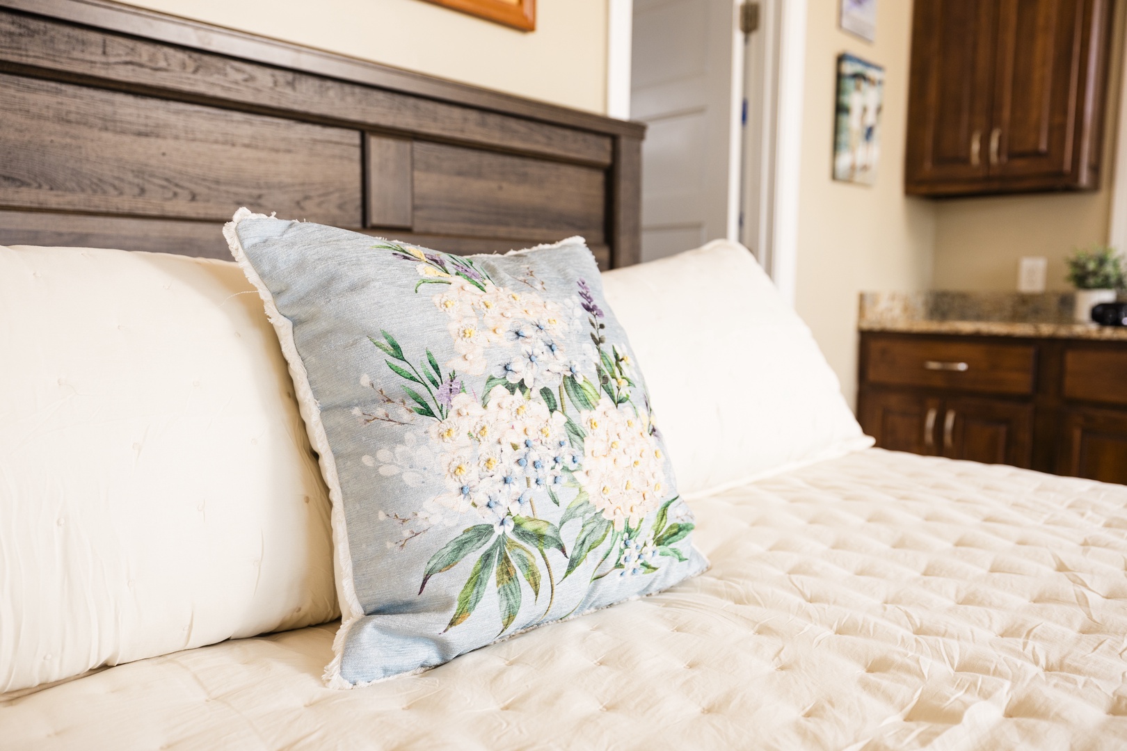 Sink into soft linens adorned with delicate floral pillows, where your peaceful retreat awaits in this thoughtfully appointed bedroom.
