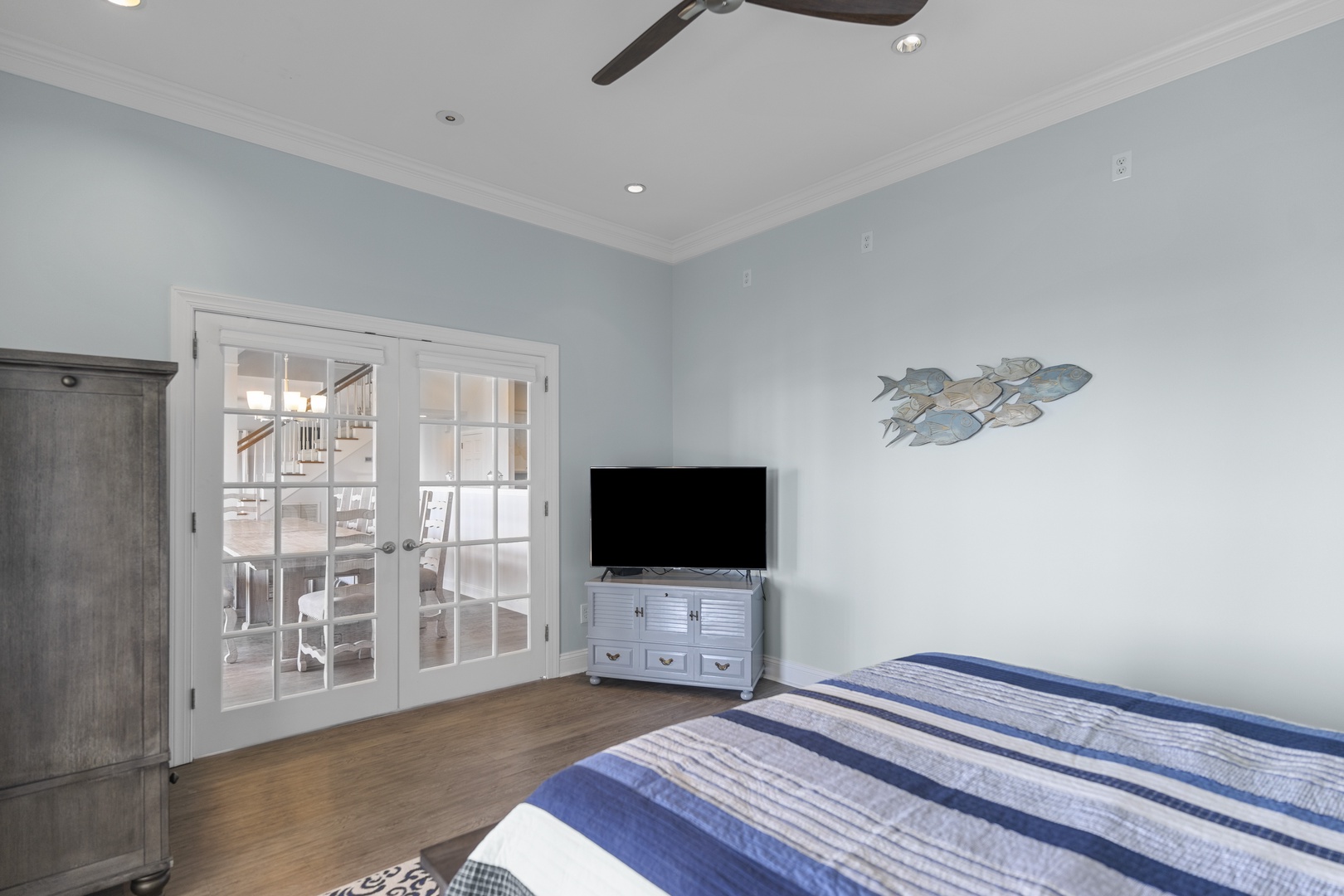 Relax in your coastal-themed bedroom with calming blue tones, ceiling fan, and private balcony access through French doors.