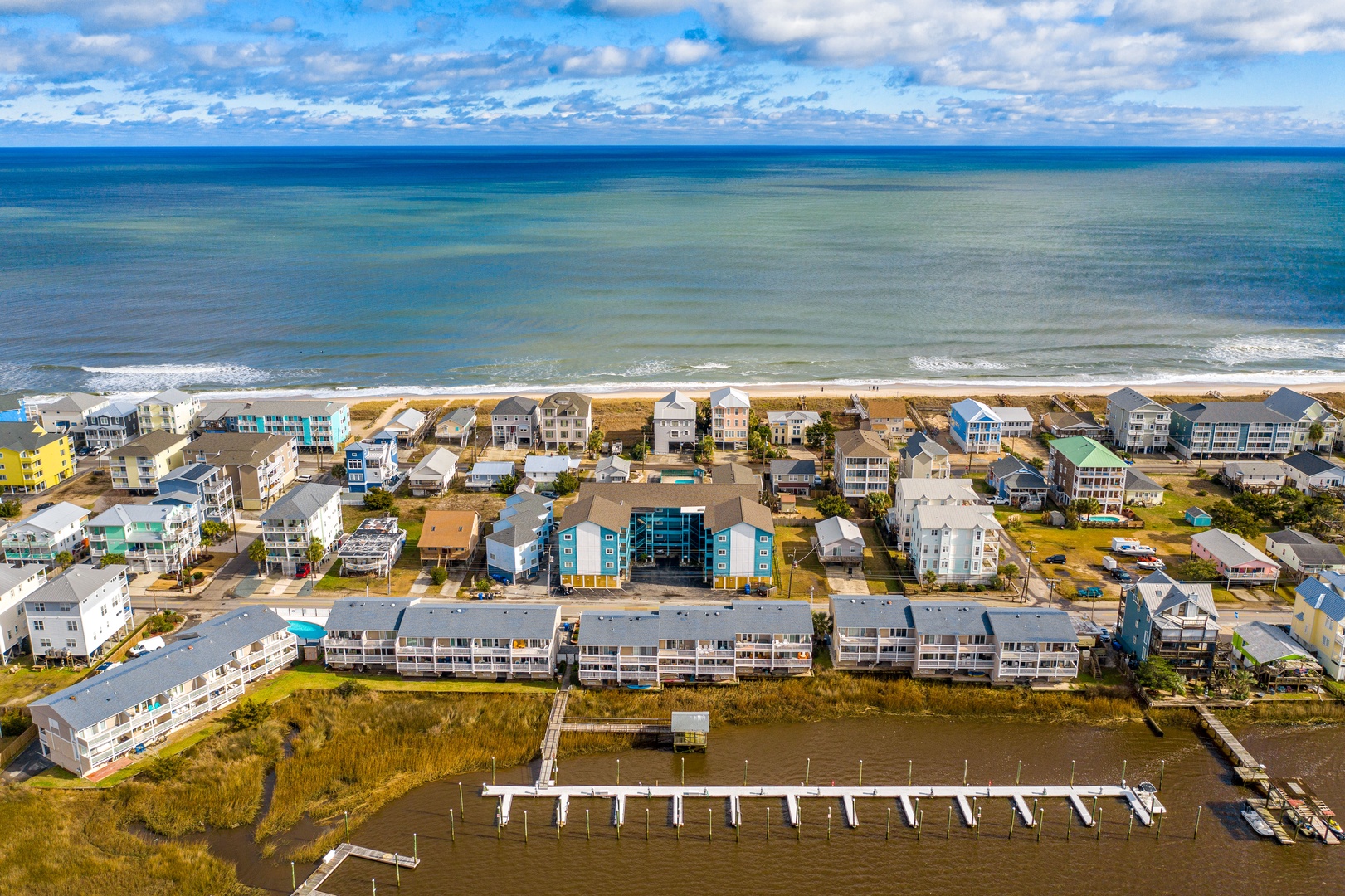 Aerial view showcasing beachfront vacation homes and nearby marina facilities along this coastal community.