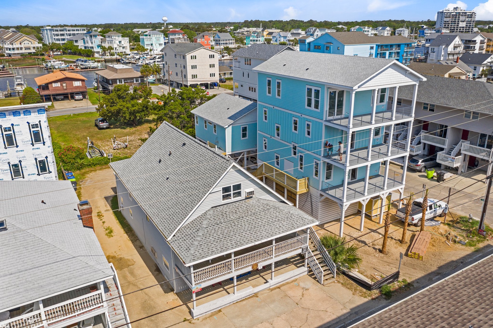Aerial view of coastal vacation rental properties nestled in a charming beachside neighborhood with colorful homes and community amenities nearby.
