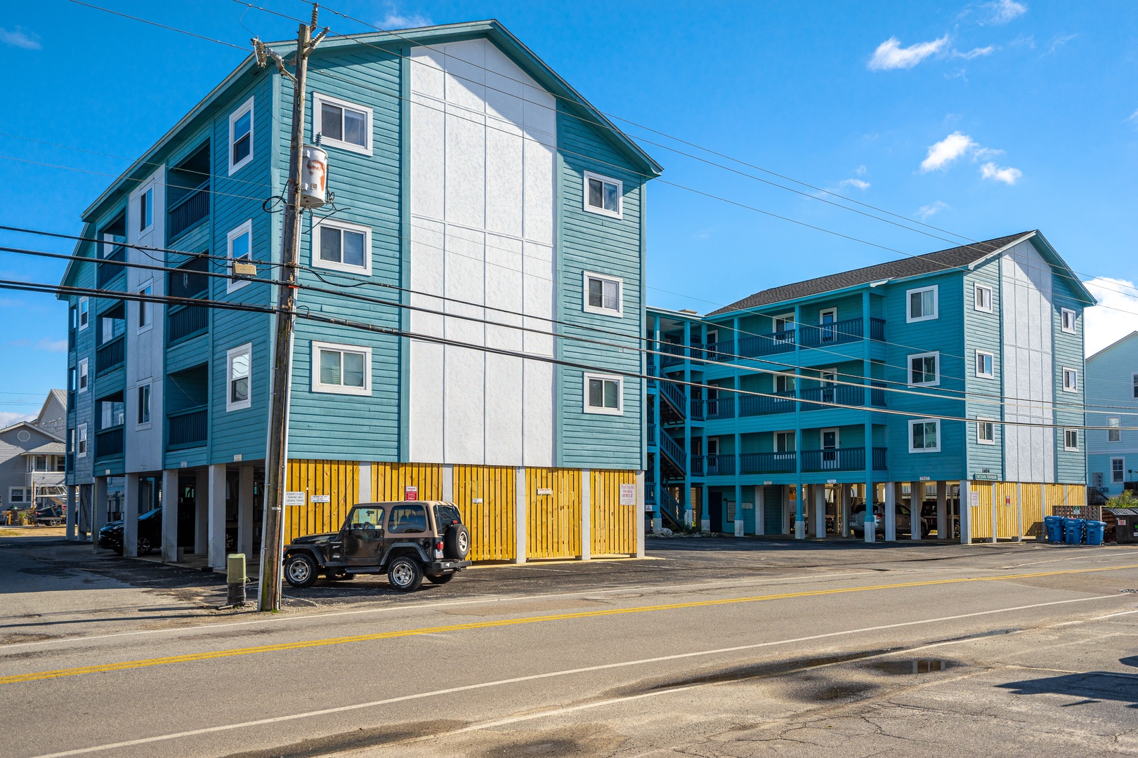 Coastal vacation rental buildings with bright teal and yellow accents stand ready for your beachside getaway.