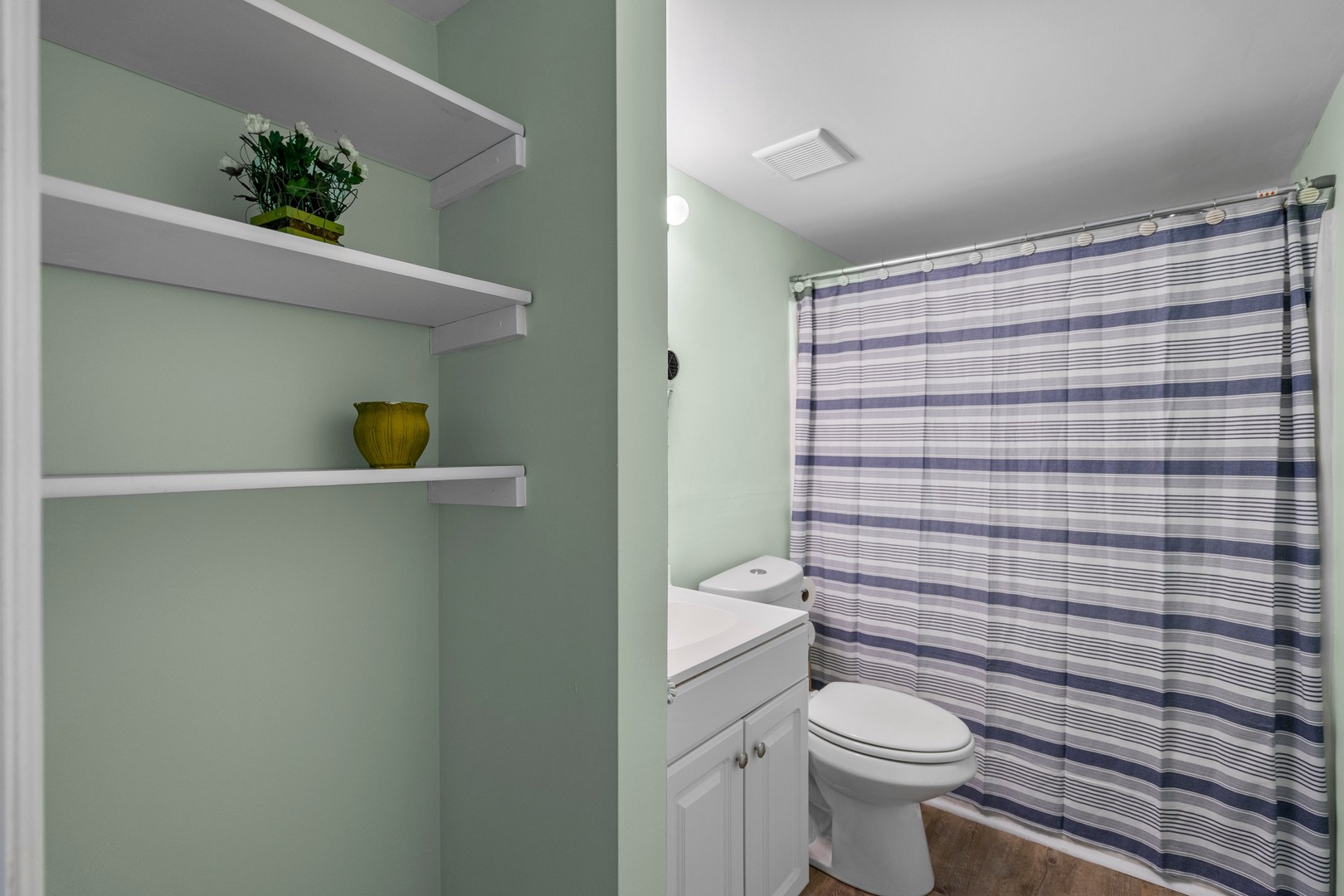Your private bathroom features a refreshing shower, thoughtful storage shelves, and calming mint-green walls that create a spa-like atmosphere.