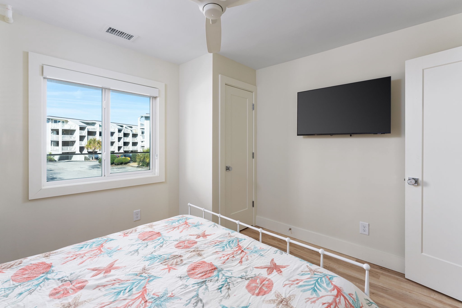 Rest peacefully in your bright bedroom with cheerful tropical bedding, wall-mounted TV for evening entertainment, and convenient wardrobe storage for all belongings.
