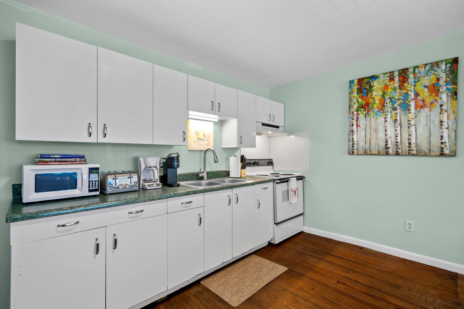 Your fully equipped kitchen features modern appliances, ample counter space, and charming mint green walls that create a fresh, welcoming atmosphere for preparing meals.