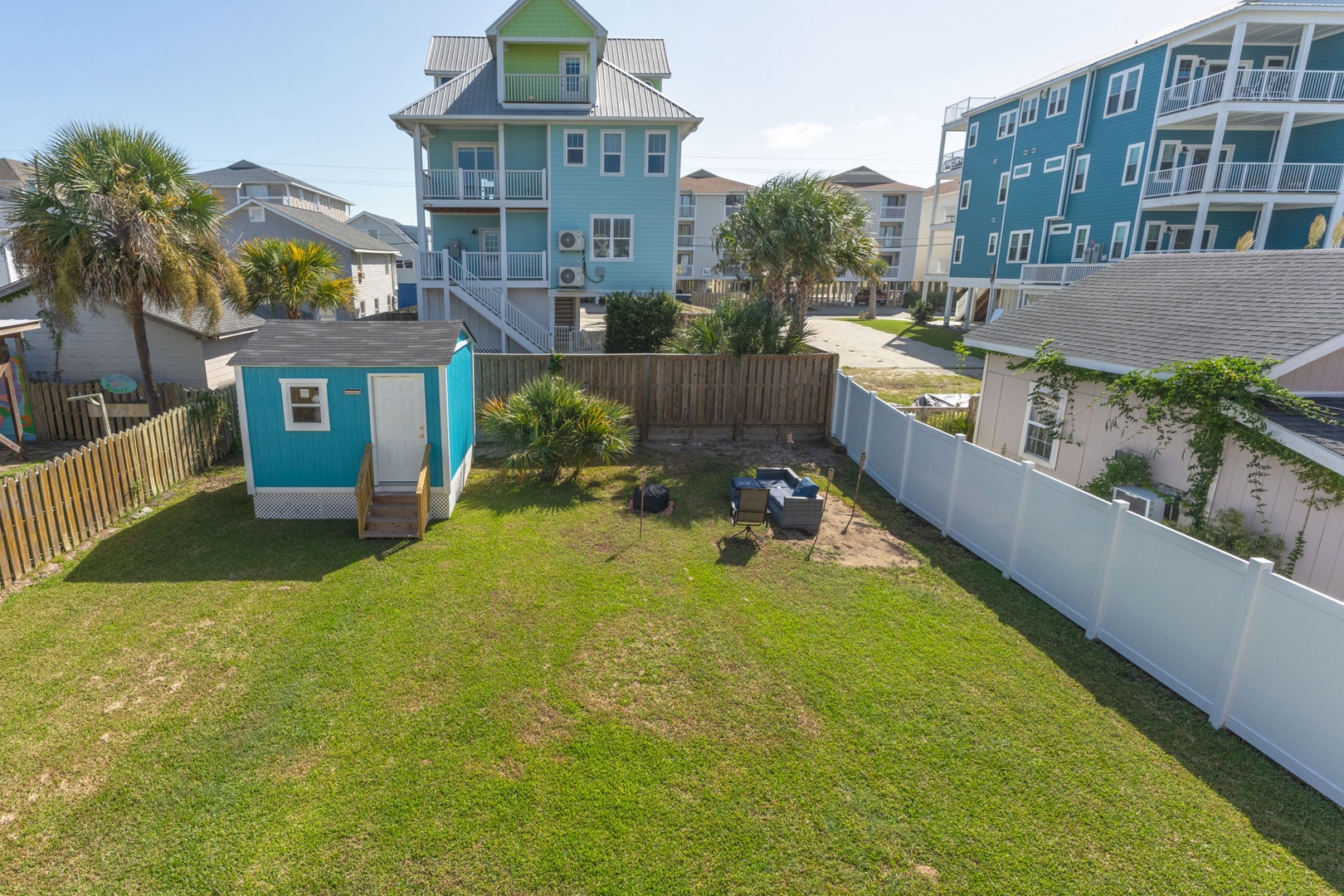Colorful coastal neighborhood with beach houses featuring palm trees and tropical landscaping in a residential setting.