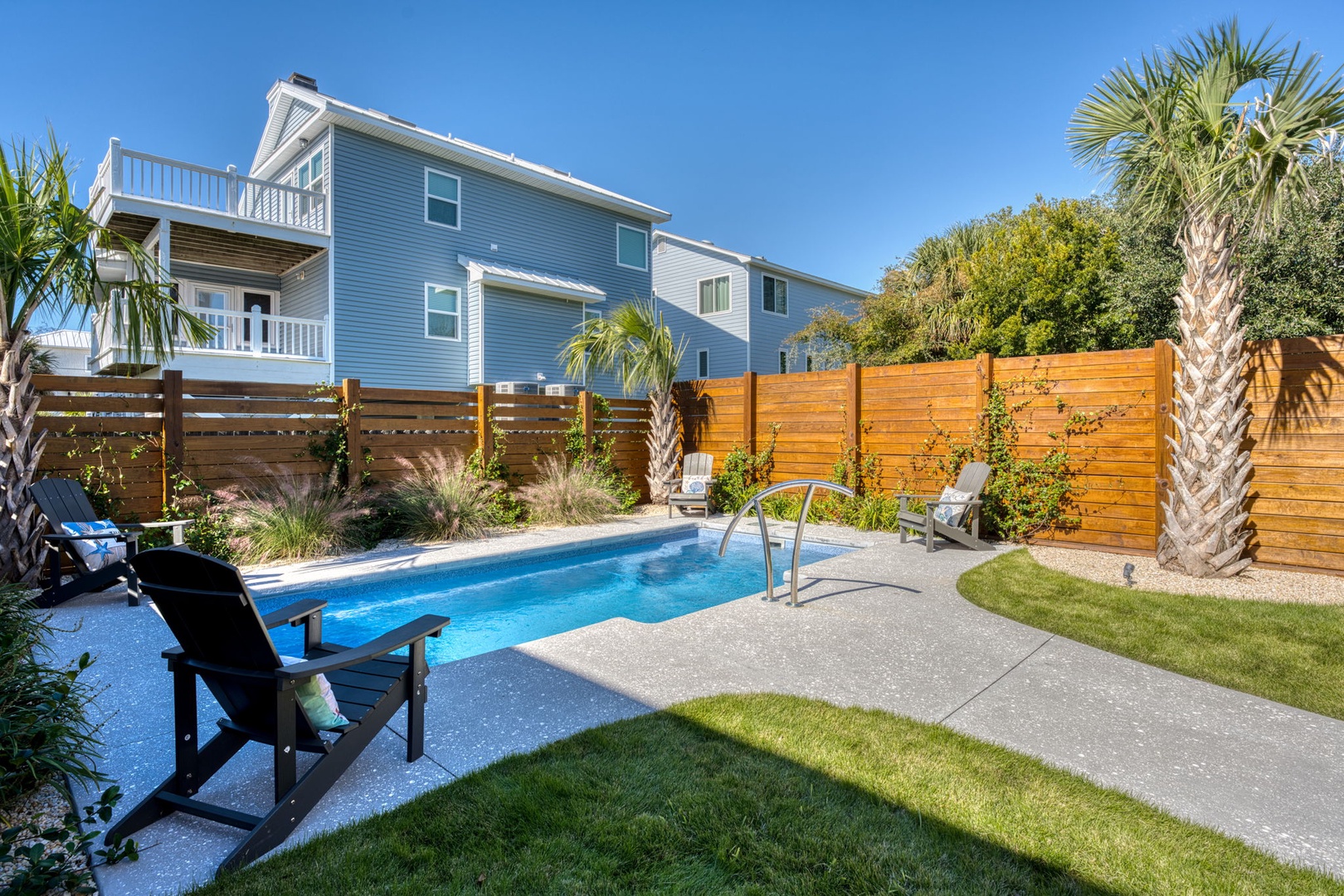 Dive into your private oasis with this sparkling pool surrounded by lush palms and tropical landscaping in your secluded backyard retreat.