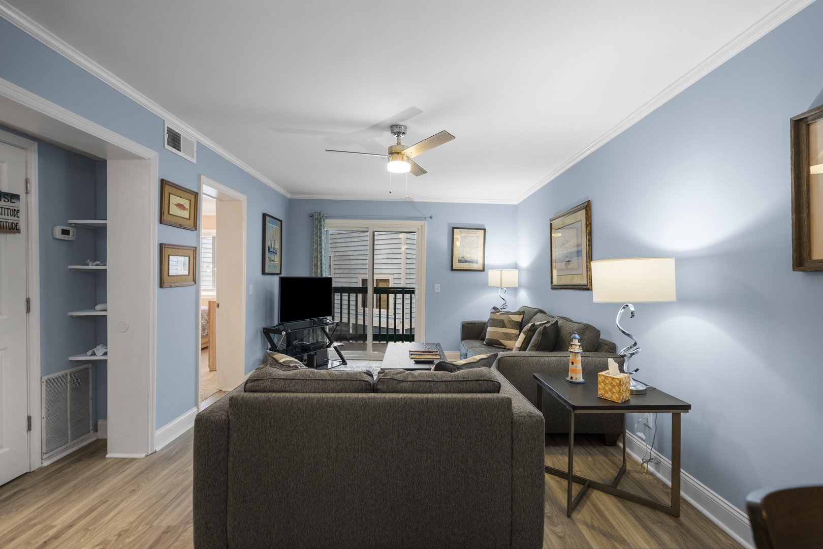 Sink into plush sofas in your calming blue living room, where coastal artwork and warm lighting create the perfect space to unwind.