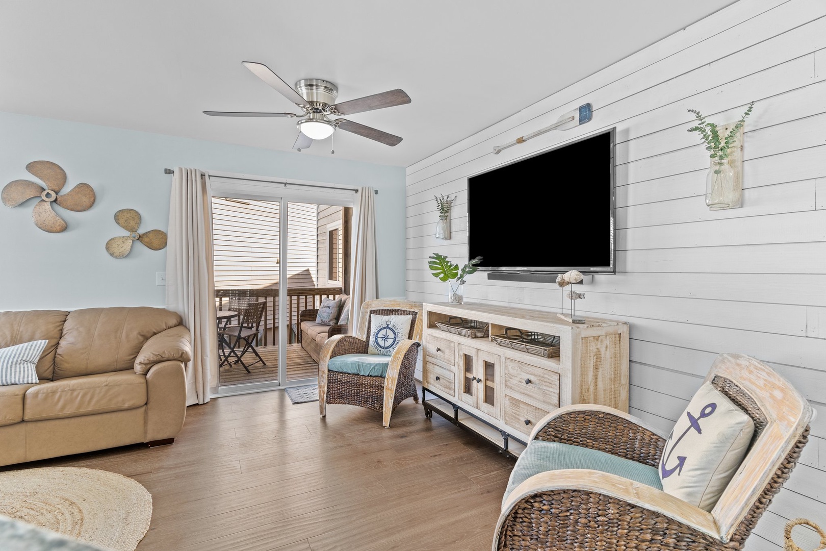 Relax in your coastal living room with shiplap walls, nautical touches, and a ceiling fan keeping you cool while you enjoy entertainment.