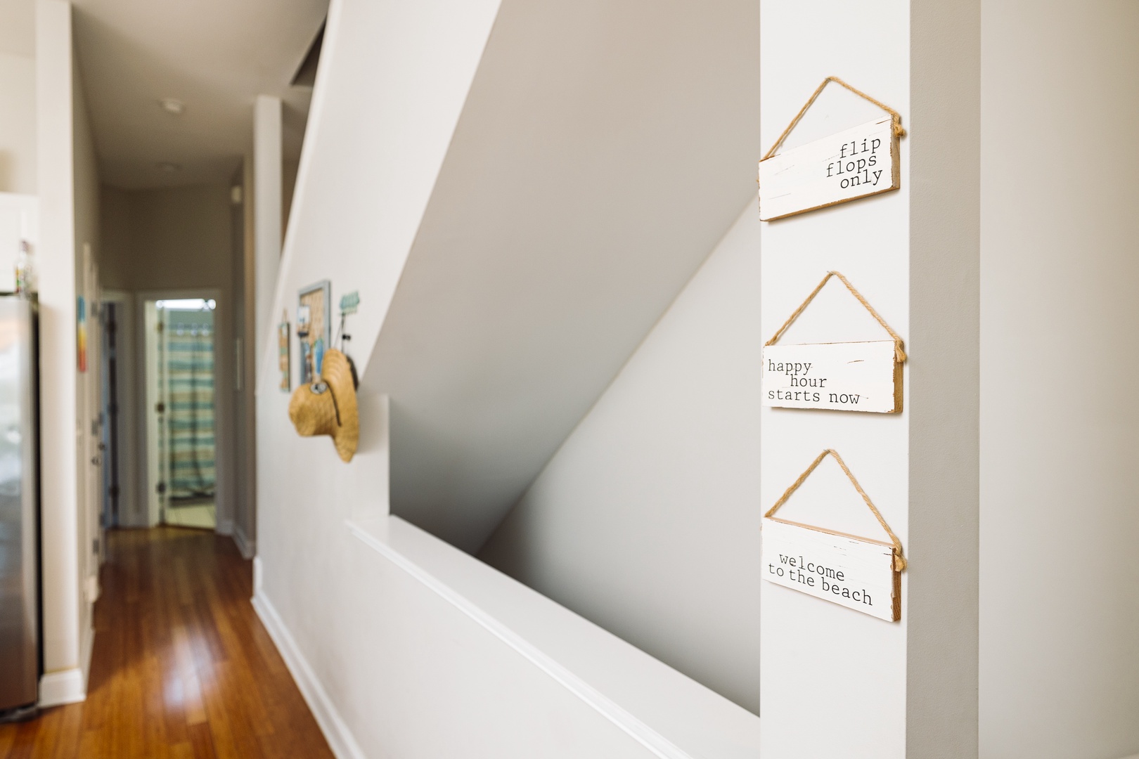 Warm wooden floors guide you through this welcoming hallway, where charming coastal signs hint at beach adventures ahead.