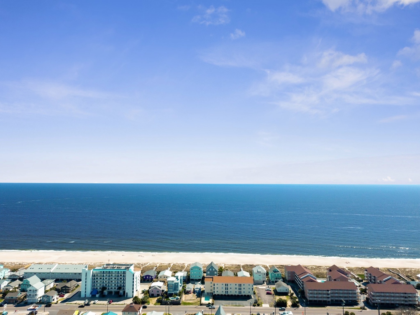 Stunning aerial view of the beachfront area with pristine ocean waters and colorful coastal buildings.