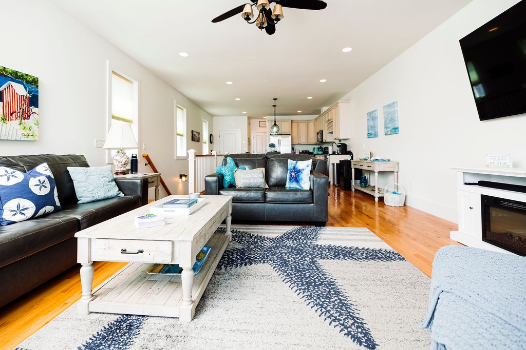 Unwind in your bright open-concept living space with cozy leather seating, coastal décor, and modern kitchen perfect for relaxing evenings.