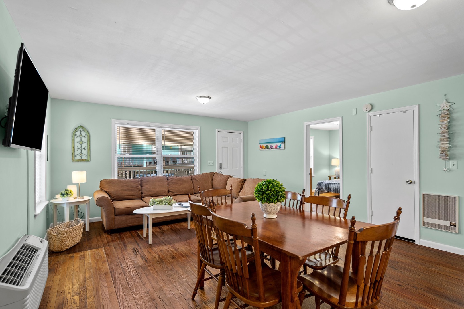 Relax in your spacious open-plan living area where soft mint walls meet warm wood floors, perfect for family meals and cozy evenings.