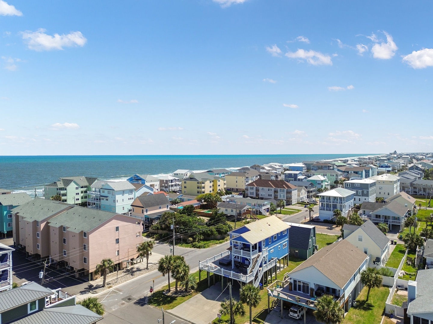 Aerial view of a charming coastal community with colorful beach houses and vacation rentals nestled along the shoreline.