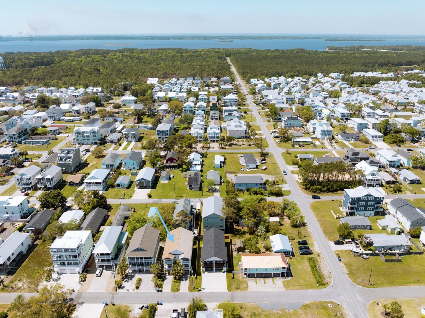 Aerial view of a charming coastal community with tree-lined streets leading toward pristine waterfront areas.