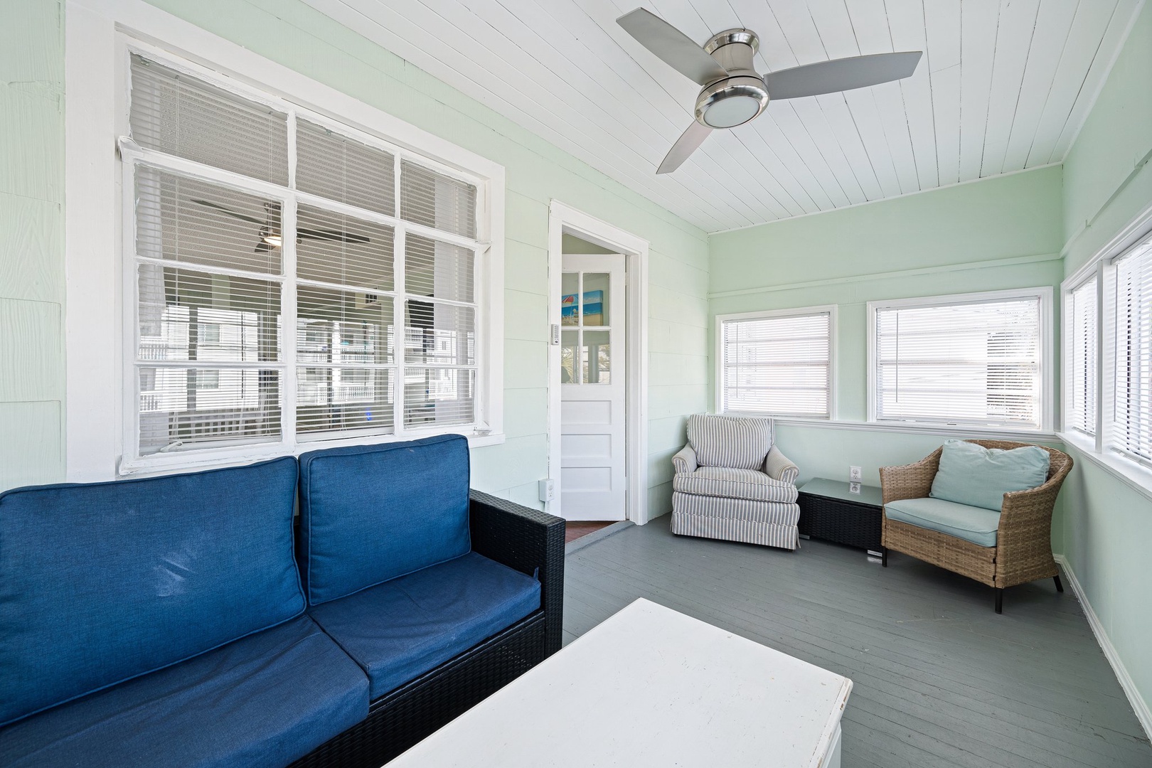 Your bright sunroom offers comfortable seating where you can relax with coffee and sea breezes flowing through coastal-style windows.