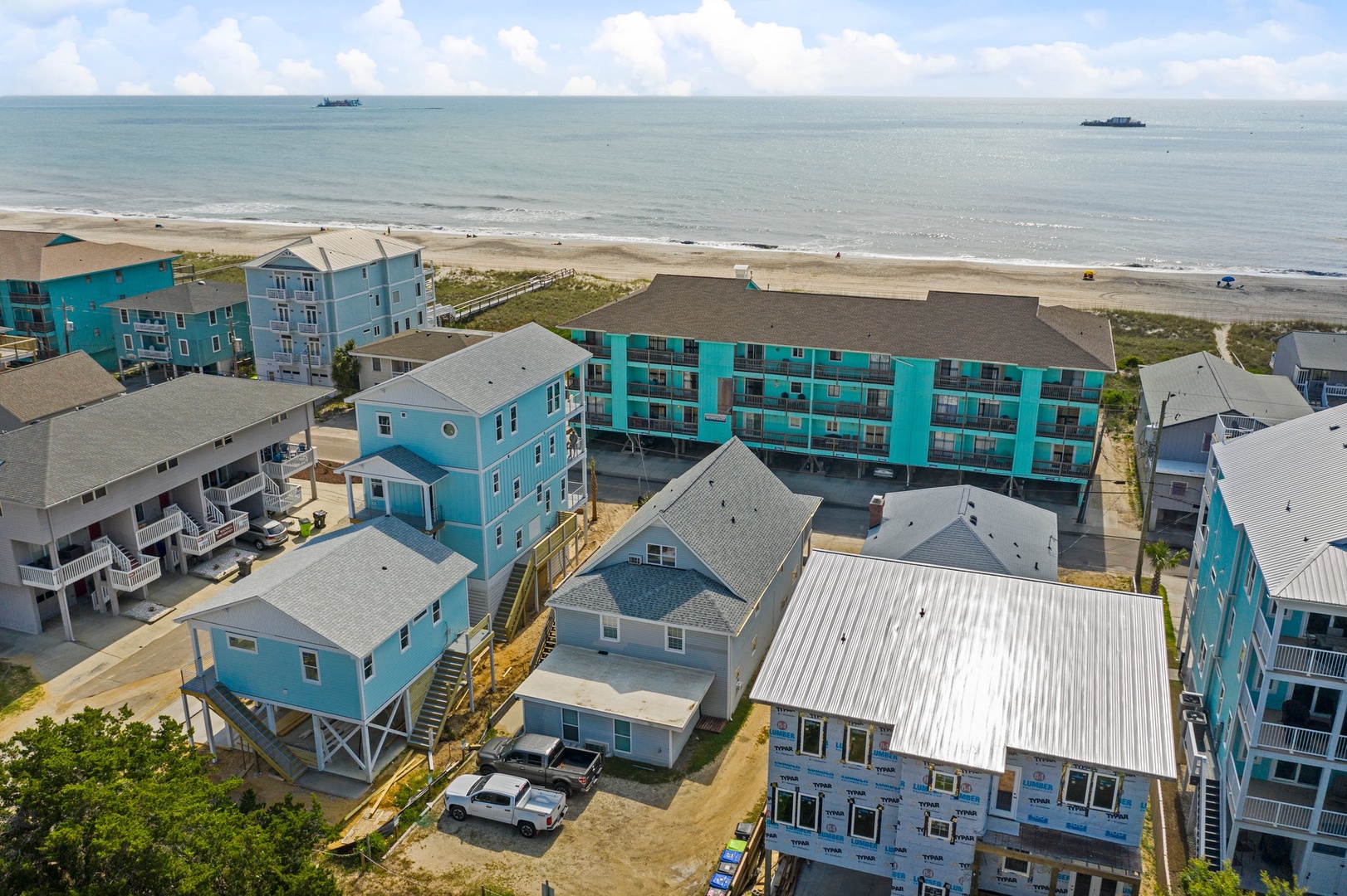 Aerial view of beachfront vacation rental properties showcasing colorful coastal buildings just steps from the sandy shore.