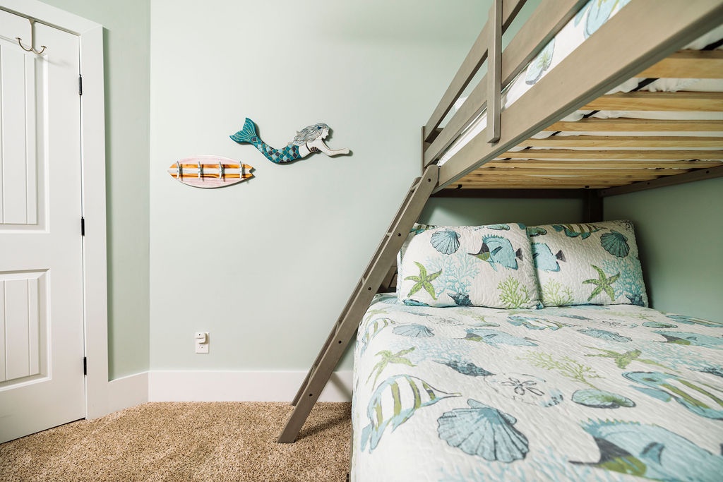 Your coastal-themed bunk room features ocean-inspired bedding and whimsical mermaid wall art, perfect for kids' seaside adventures.