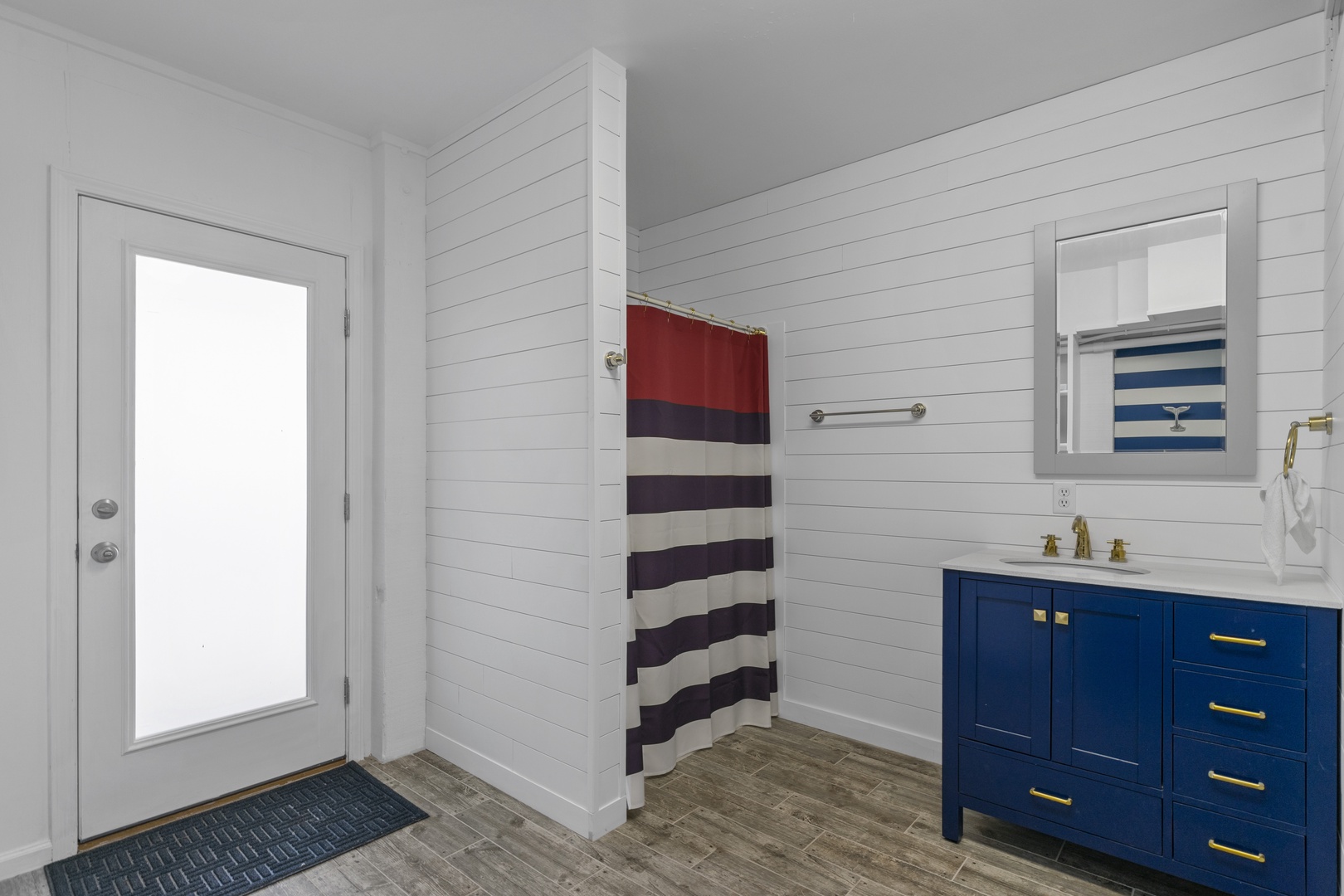 Freshen up in your crisp bathroom with nautical charm - bold navy vanity and brass fixtures create coastal elegance.