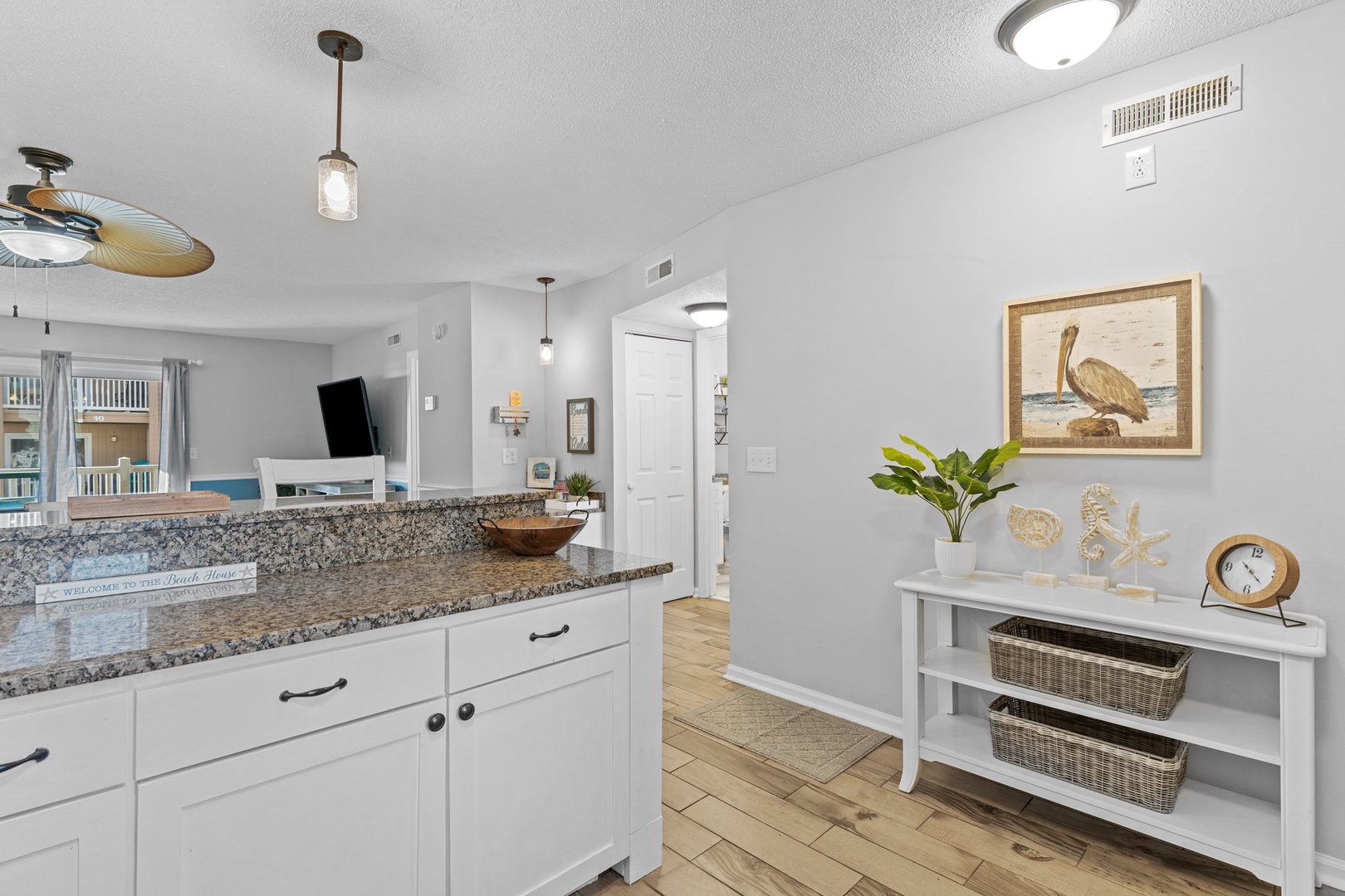 Relax in your bright coastal kitchen with granite counters, ceiling fan comfort, and charming pelican artwork creating beachy vibes.