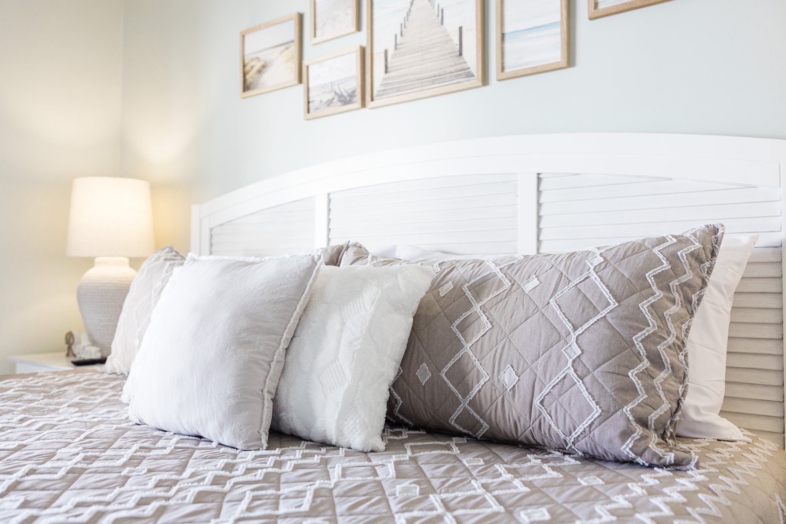 Sink into plush pillows and coastal-inspired linens in your serene bedroom retreat, where peaceful beach artwork sets the mood for relaxation.