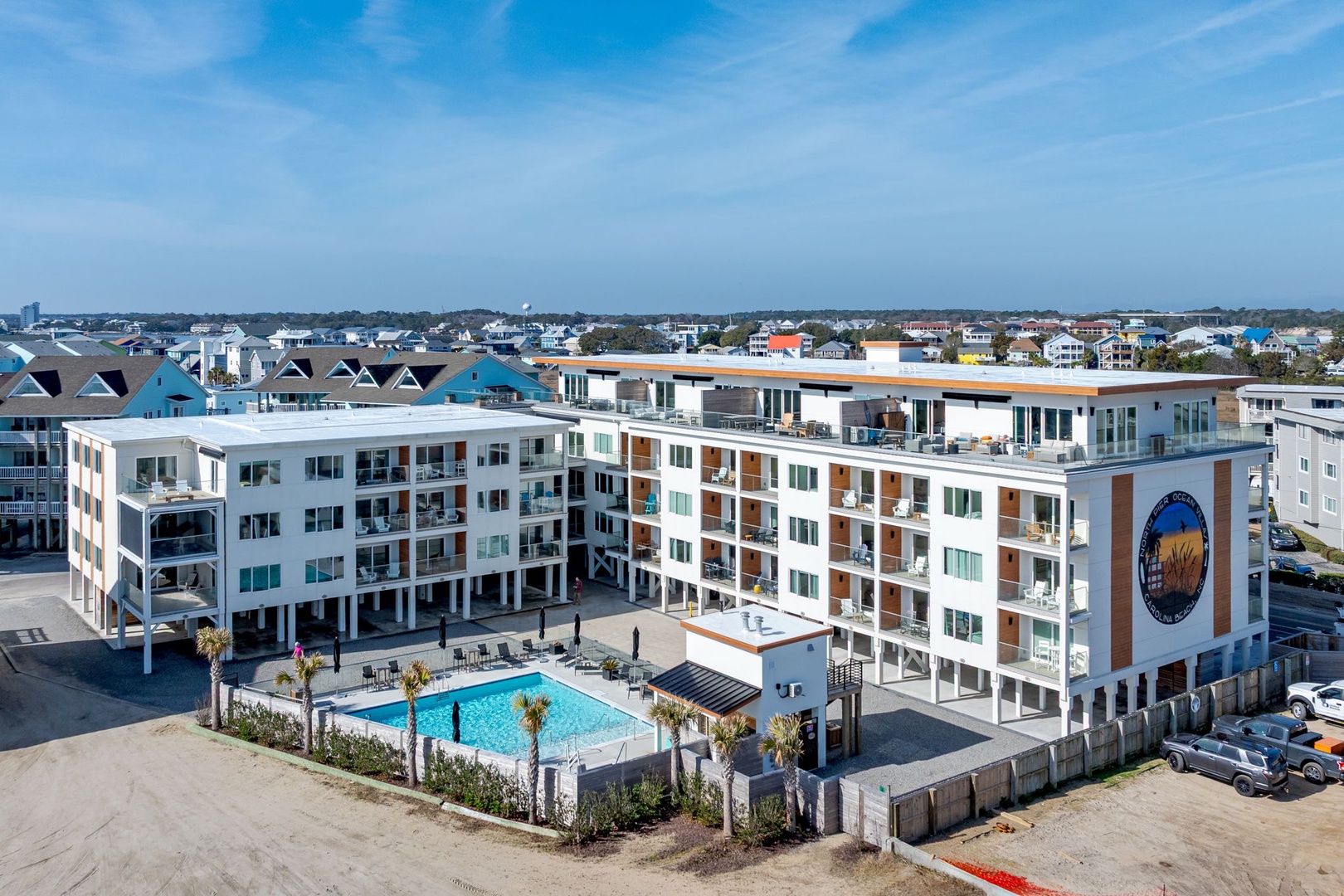 Modern beachside hotel complex with swimming pool nestled among coastal residential neighborhoods.