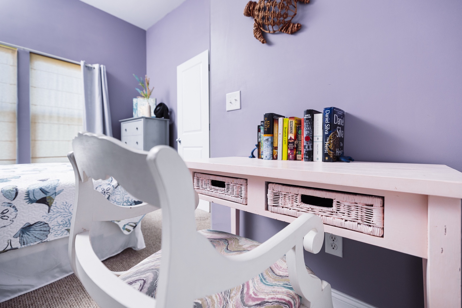 Your peaceful study nook with coastal charm - settle into the cozy reading chair surrounded by books and gentle lavender walls.