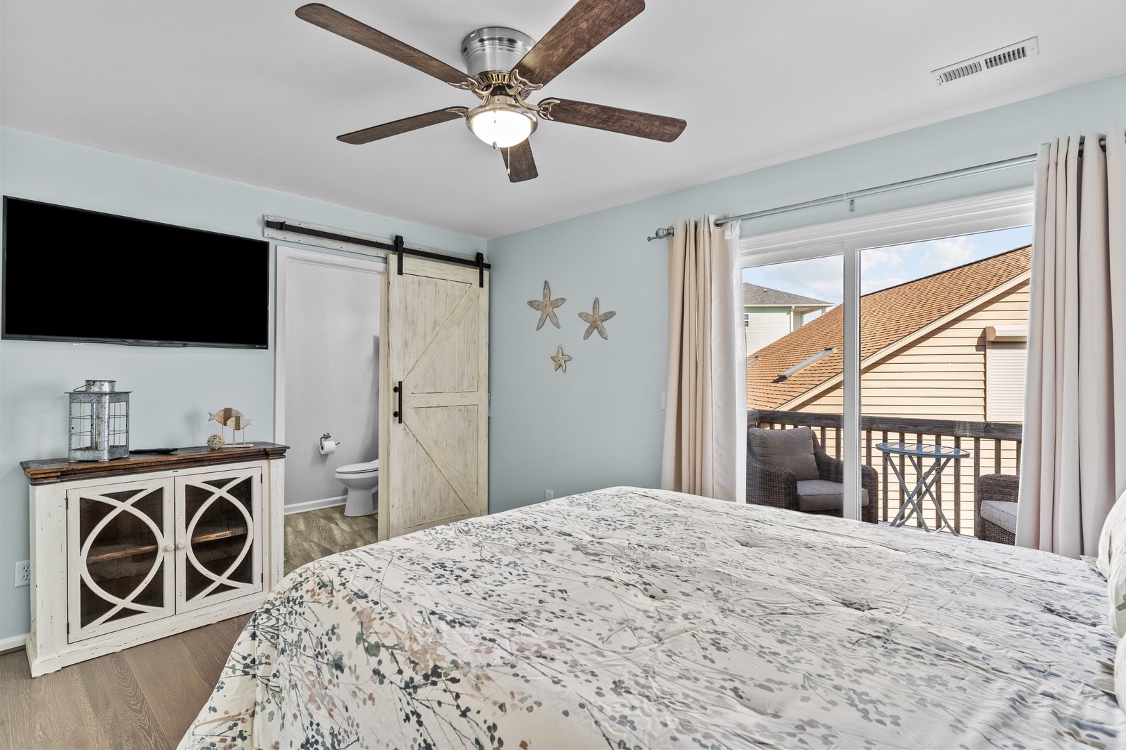 Drift off in your coastal-inspired bedroom with soothing sea glass walls, rustic barn door, and private balcony access for morning coffee moments.
