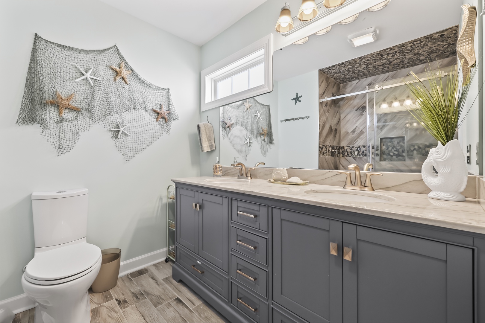 Your coastal-inspired bathroom blends nautical charm with modern comfort. Relax after a day at the beach in this serene space, featuring a dual-sink vanity and coastal décor touches.