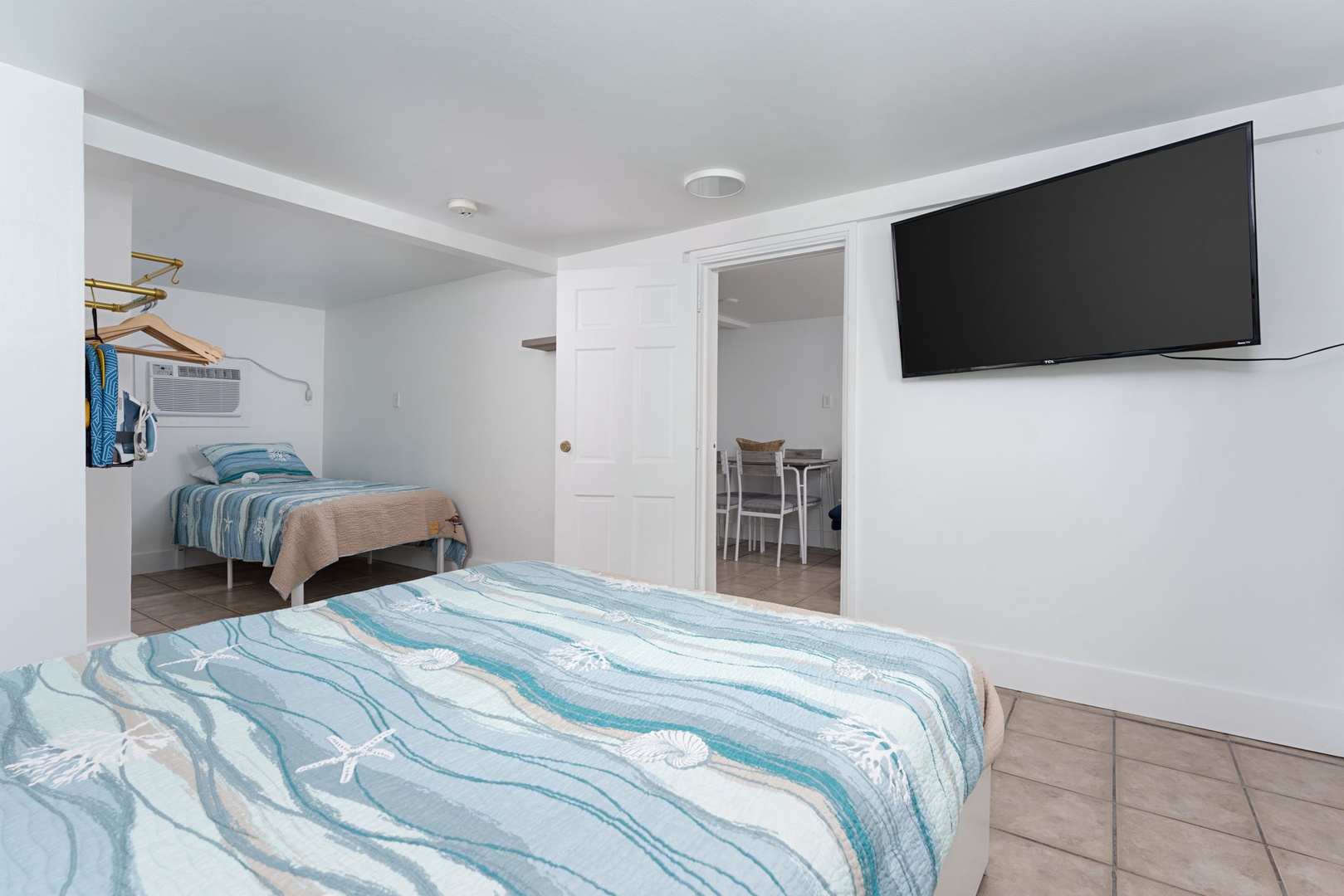 Your bright bedroom features ocean-themed bedding and a wall-mounted TV for relaxing evenings after beach adventures.