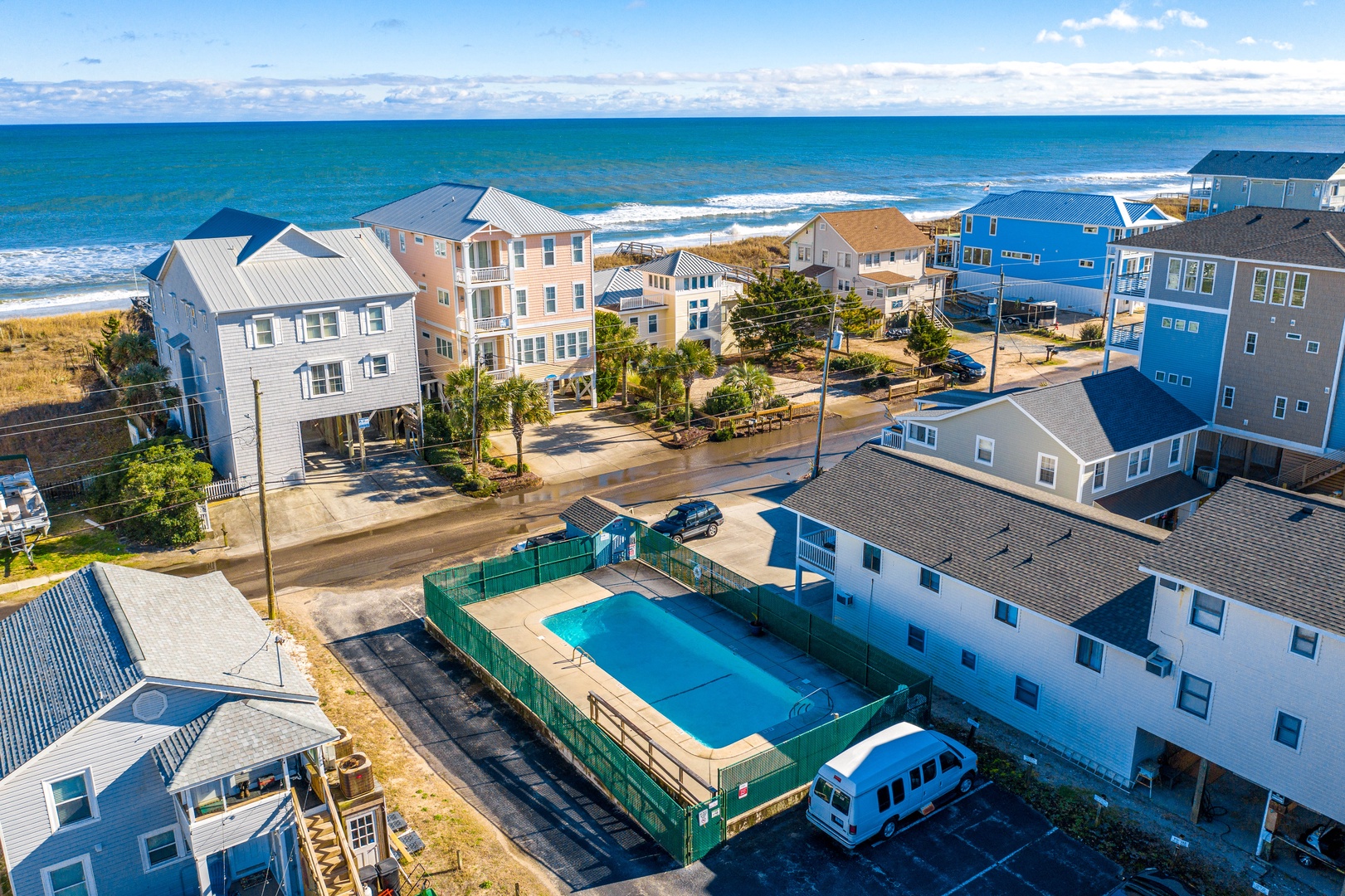 Stunning aerial view of beachfront vacation homes just steps from pristine sandy shores and sparkling ocean waves.