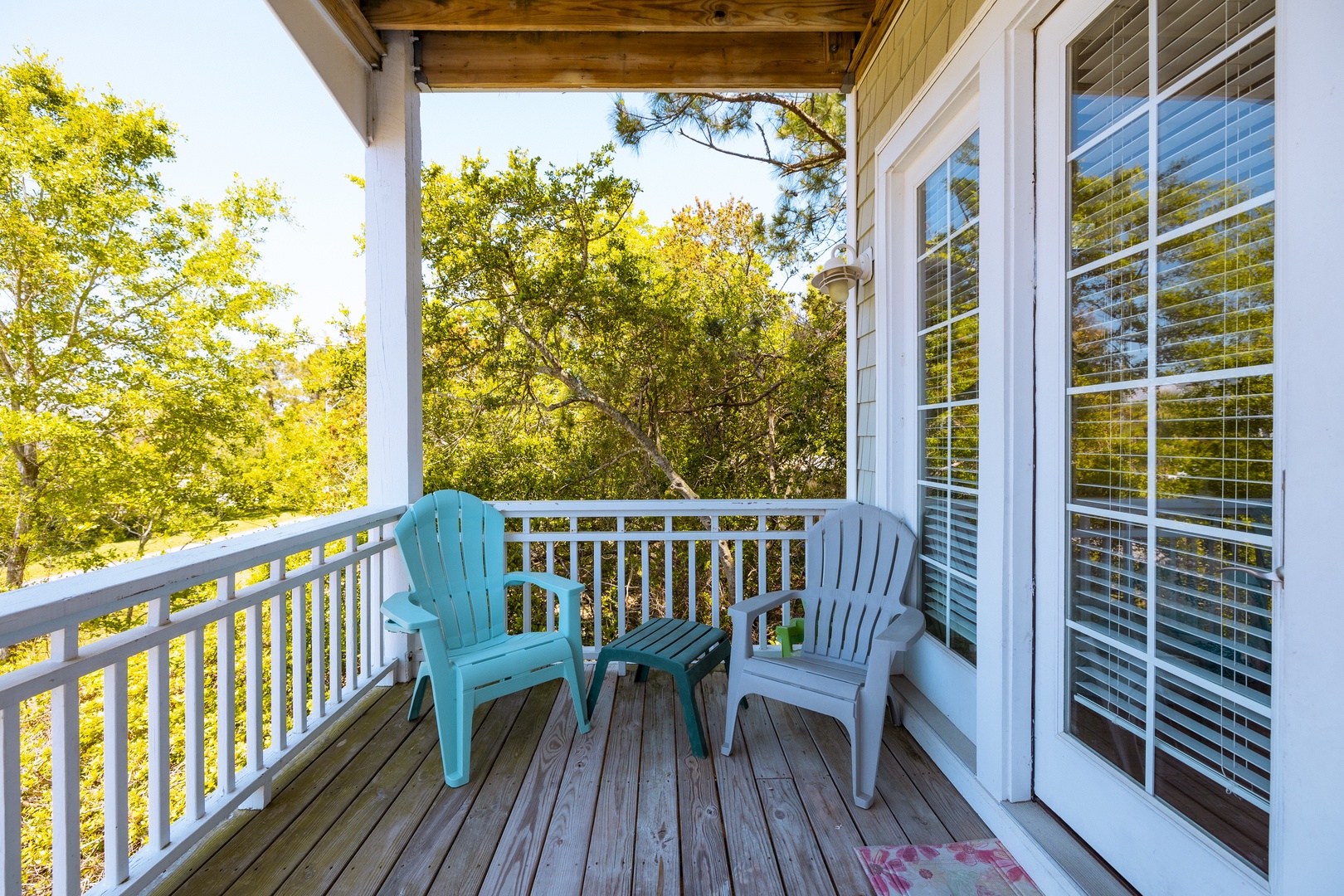 Step onto your private balcony where two cozy chairs await, overlooking peaceful treetops through the white railings.