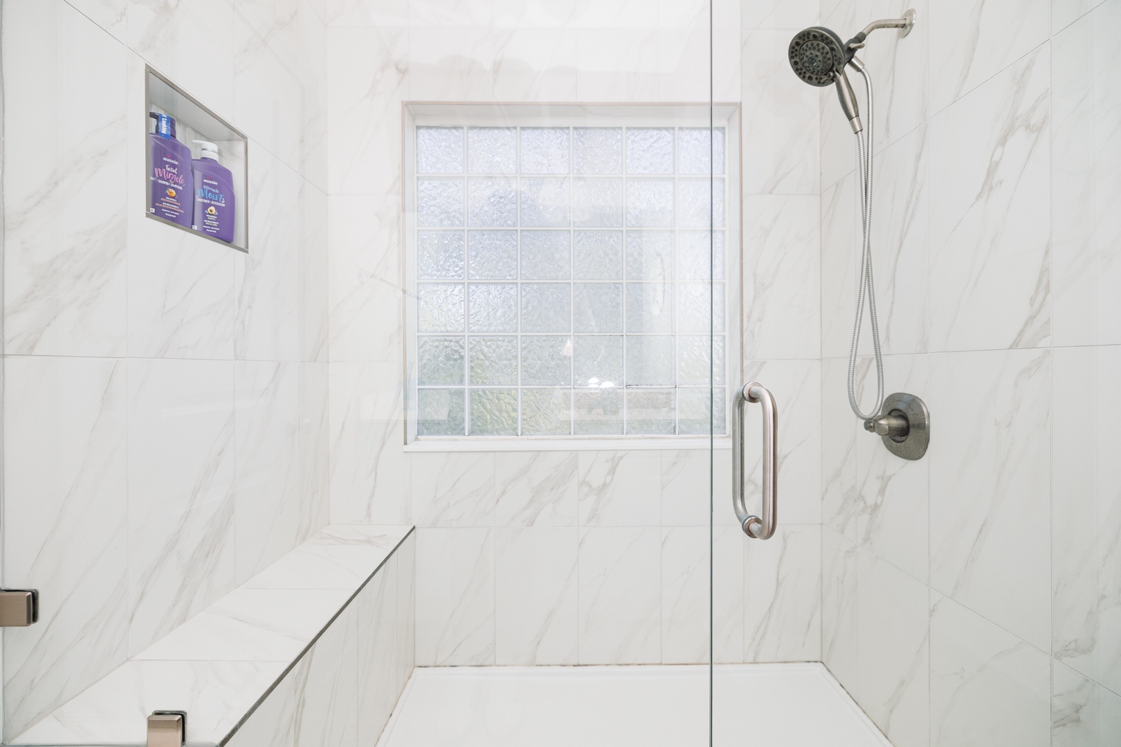 Step into your luxurious marble shower with rainfall showerhead and built-in seating for the ultimate relaxing experience.