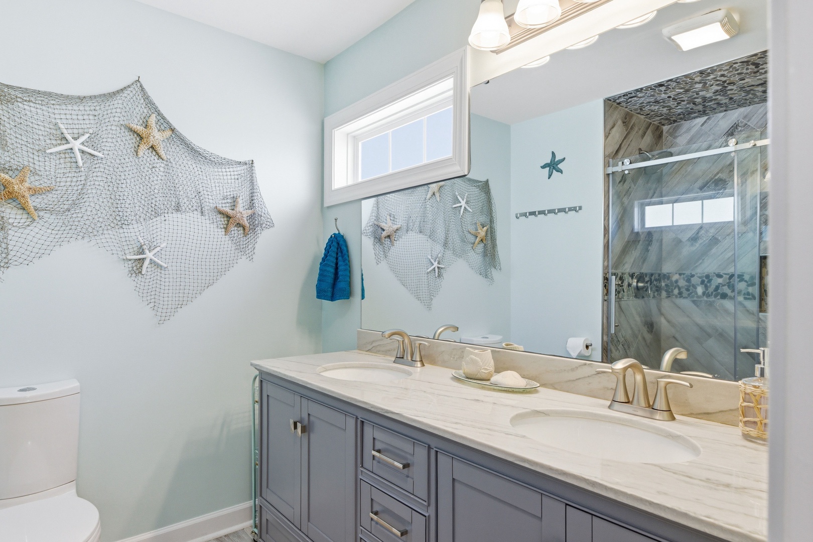 Coastal charm meets comfort in your private bathroom with ocean-inspired décor, dual vanities, and a spacious walk-in shower—your refreshing retreat after beach days.