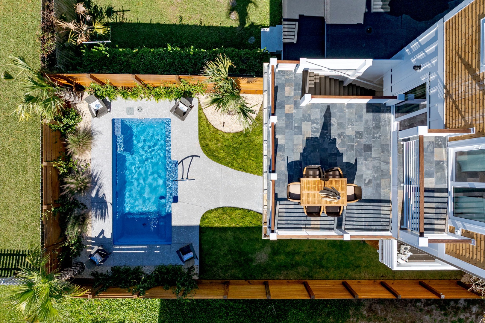 Aerial view showcasing a modern vacation rental with private swimming pool, landscaped gardens, and outdoor entertainment areas.