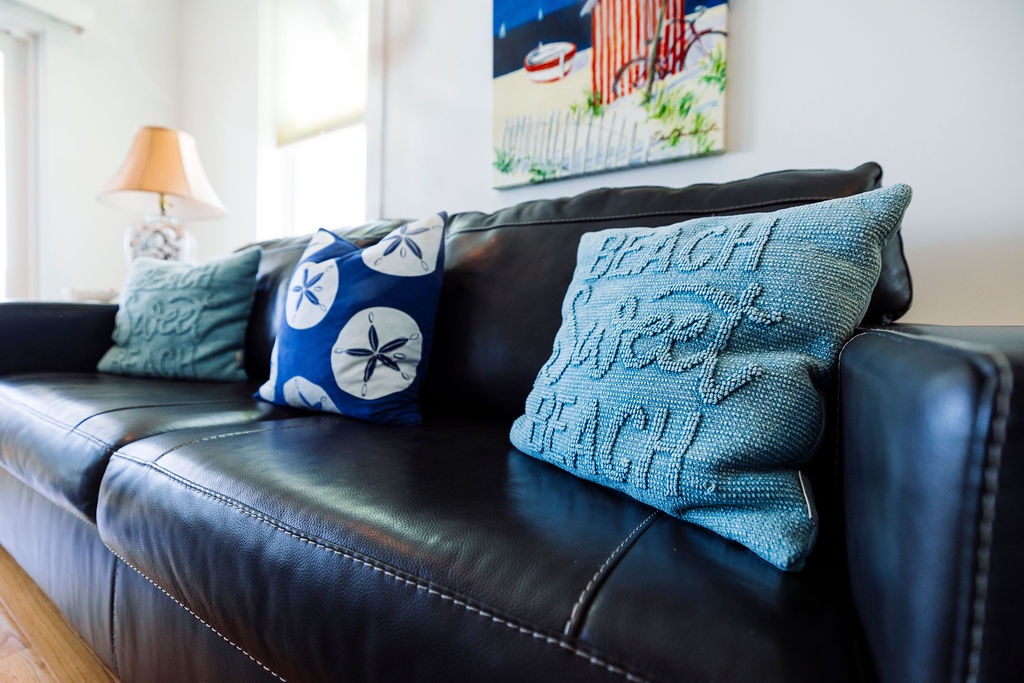 Sink into this cozy leather sofa adorned with cheerful coastal pillows, where you'll love unwinding after beach adventures.