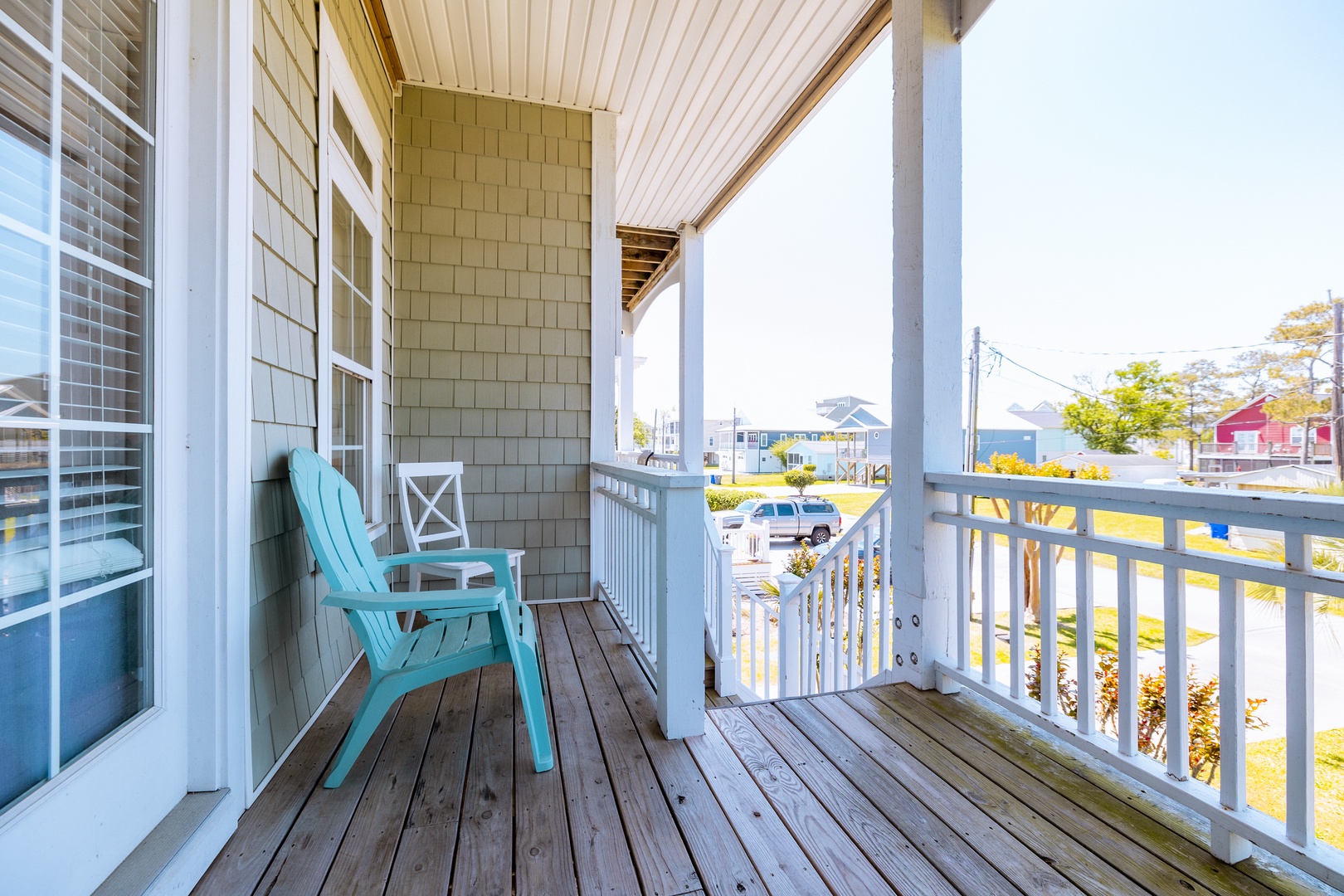 Unwind on your private covered porch with turquoise Adirondack chairs, watching neighborhood life unfold while enjoying the coastal breeze.