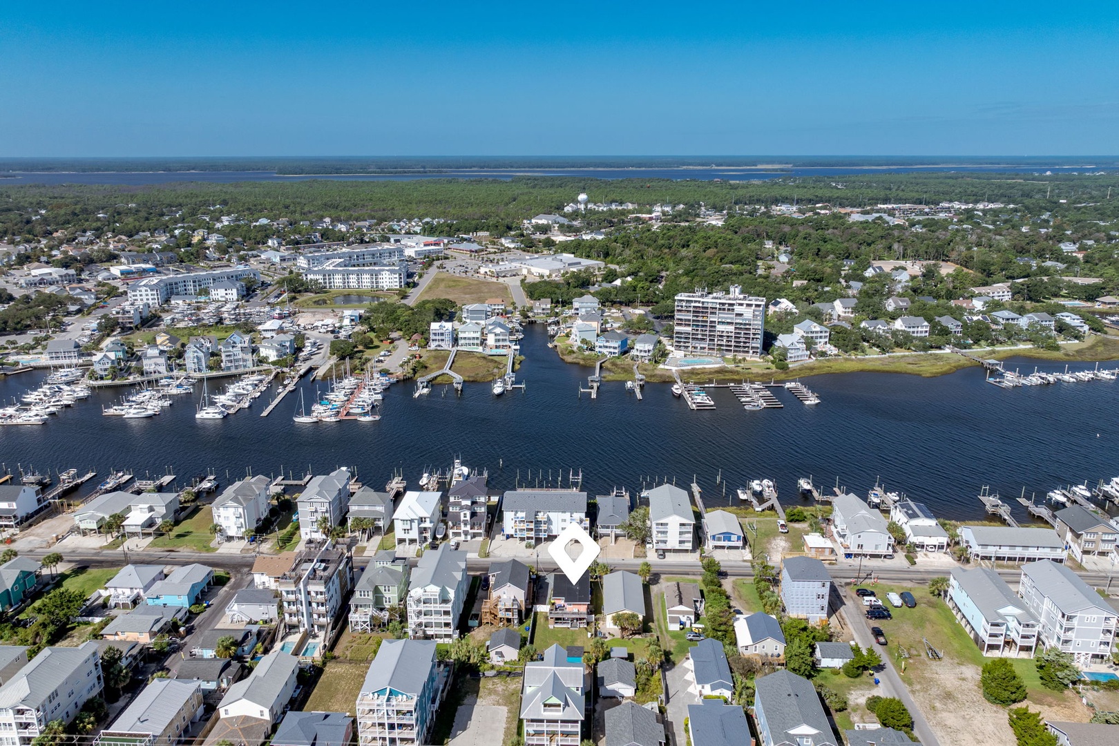Aerial view of a coastal marina community with waterfront homes, boat docks, and ocean access in a picturesque seaside town.