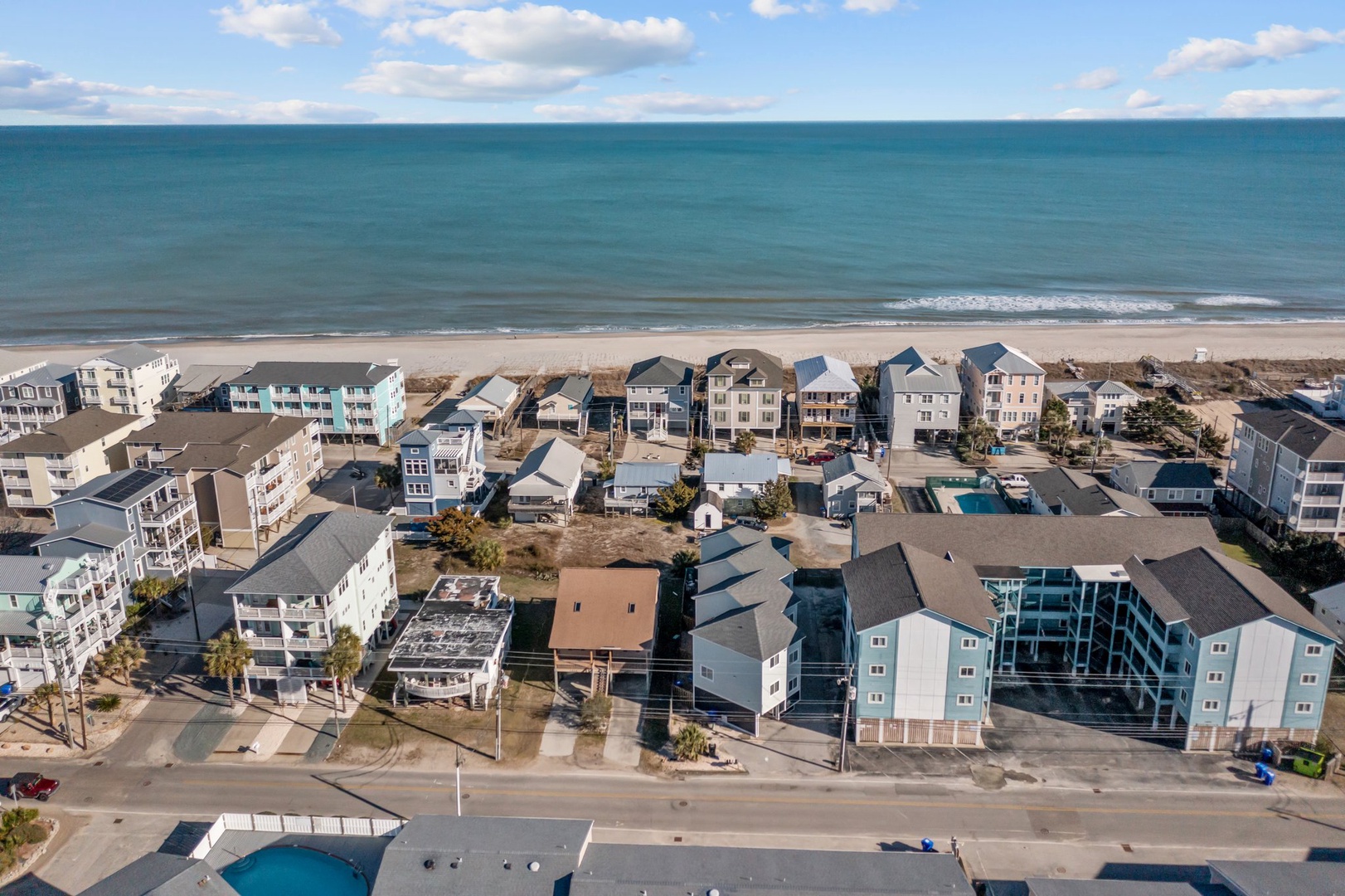 Aerial view of beachfront vacation rental community with colorful coastal homes just steps from sandy shores.