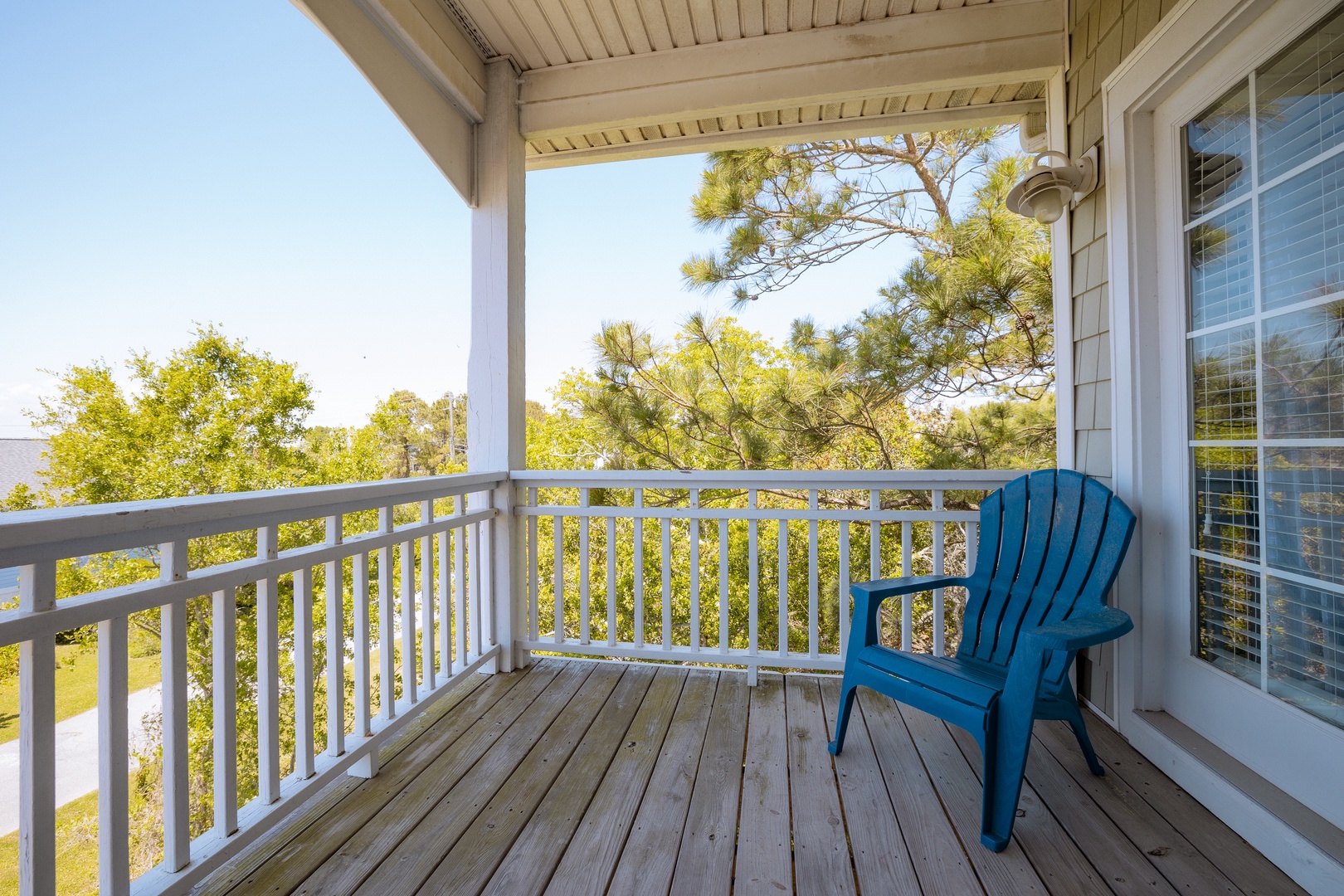 Step onto your private covered balcony and settle into the blue chair, where treetop views and gentle breezes create the perfect spot for morning coffee or evening relaxation.