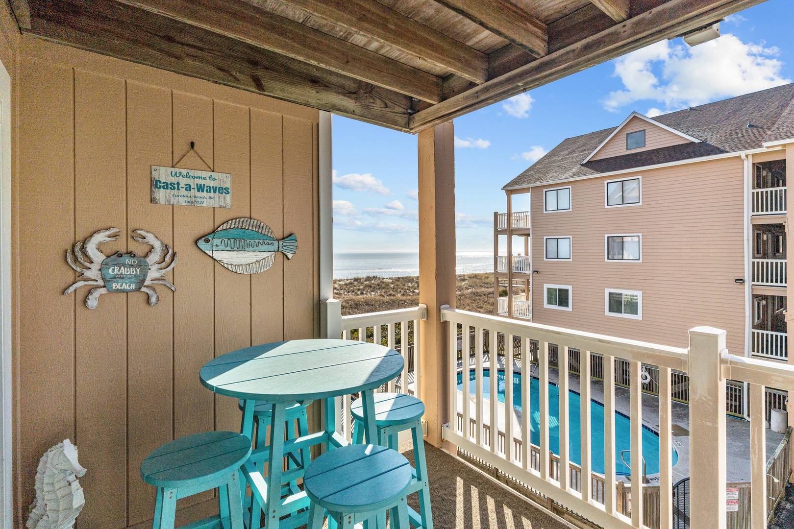 Unwind on your private balcony with charming coastal decor and turquoise seating, perfectly positioned to soak up ocean breezes and pool views.
