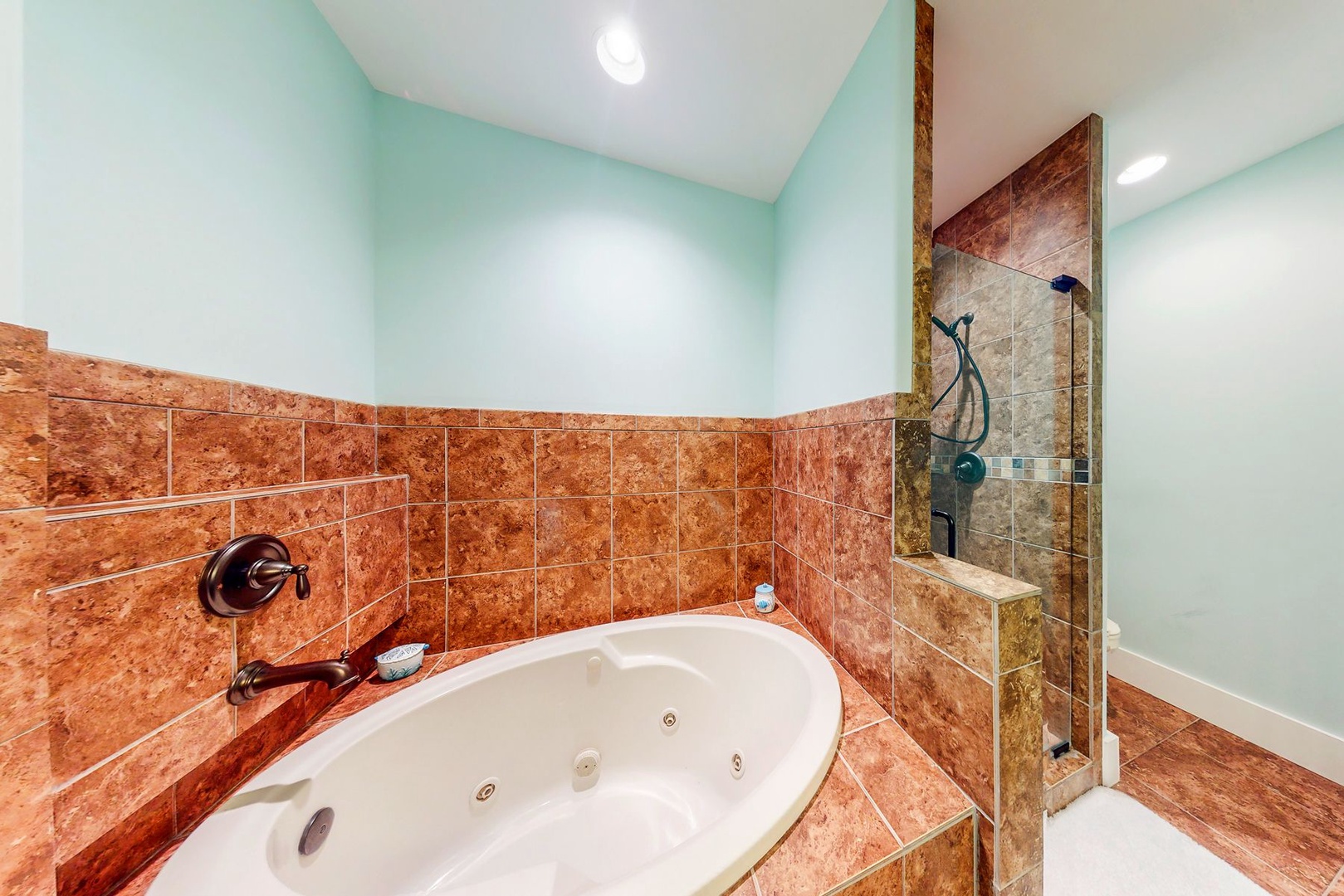Unwind in your private spa-like bathroom with a luxurious jetted tub and elegant stone shower for ultimate relaxation.