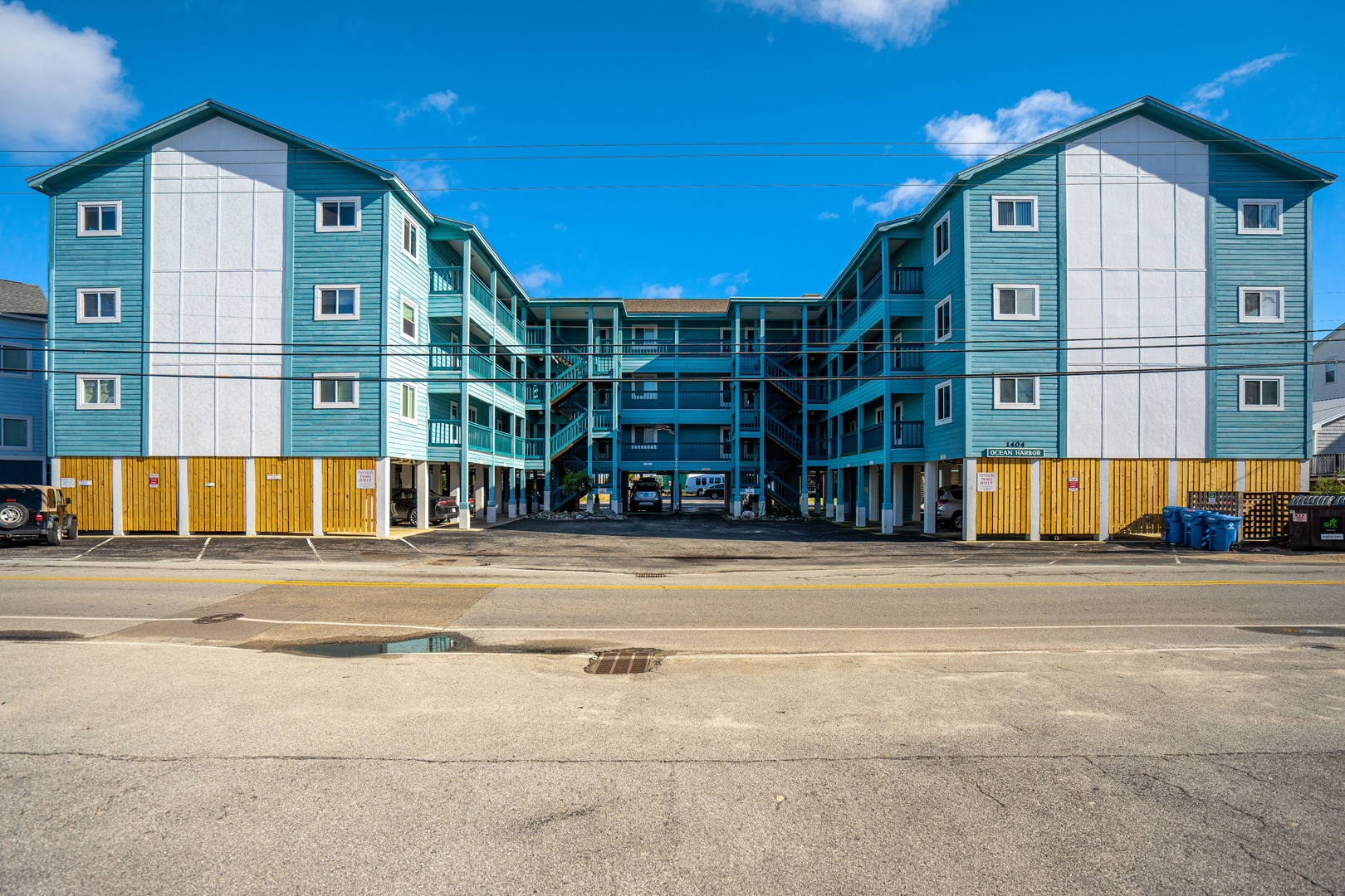 Modern blue and white property building featuring multiple levels with convenient ground-floor parking and balconies throughout.