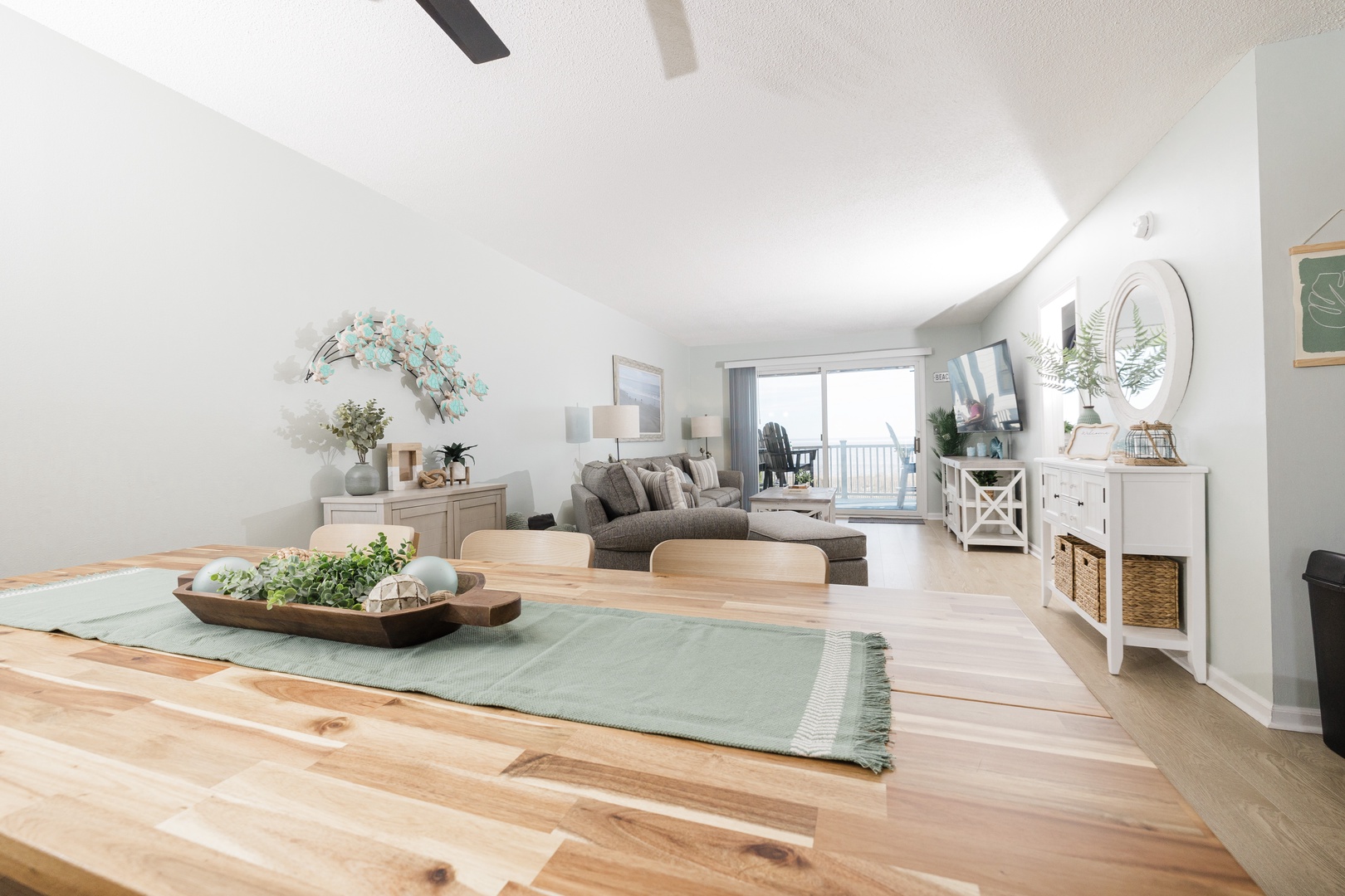 Relax in your bright, airy living space where natural light flows through large windows onto warm wood floors and cozy seating.