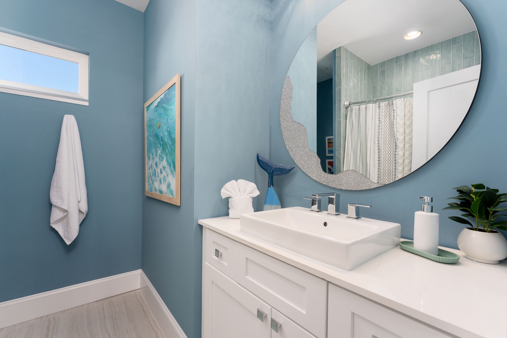 Refresh in your serene coastal bathroom with soothing blue walls, modern vanity, and ocean-inspired artwork creating a spa-like retreat.