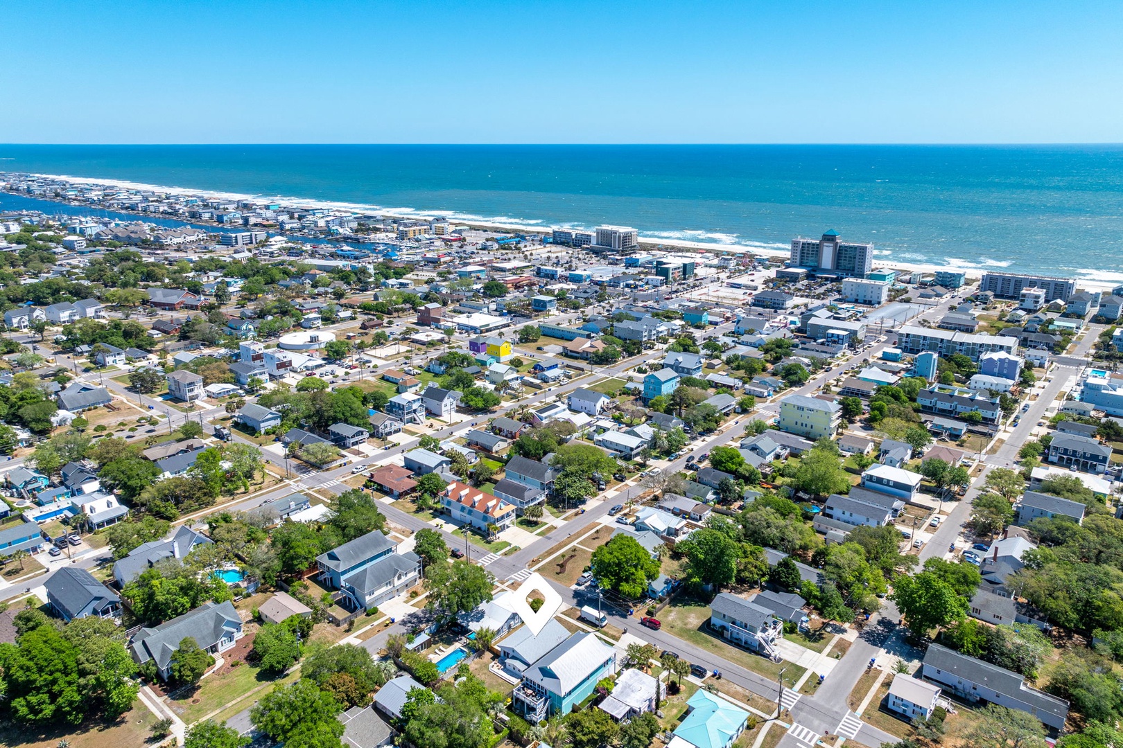Aerial view of beachfront community with tree-lined residential streets leading to pristine coastline and blue ocean waters.