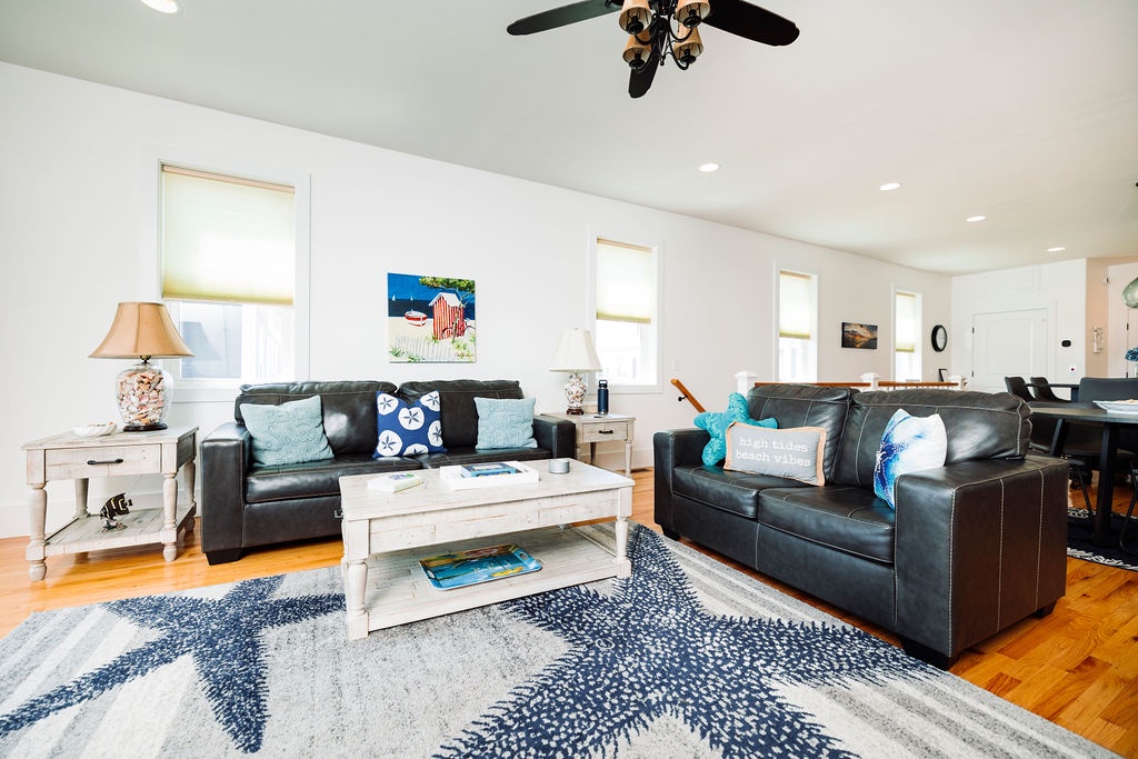 Sink into plush leather sofas in this bright, coastal-themed living room where nautical touches and gleaming hardwood floors create your perfect retreat.